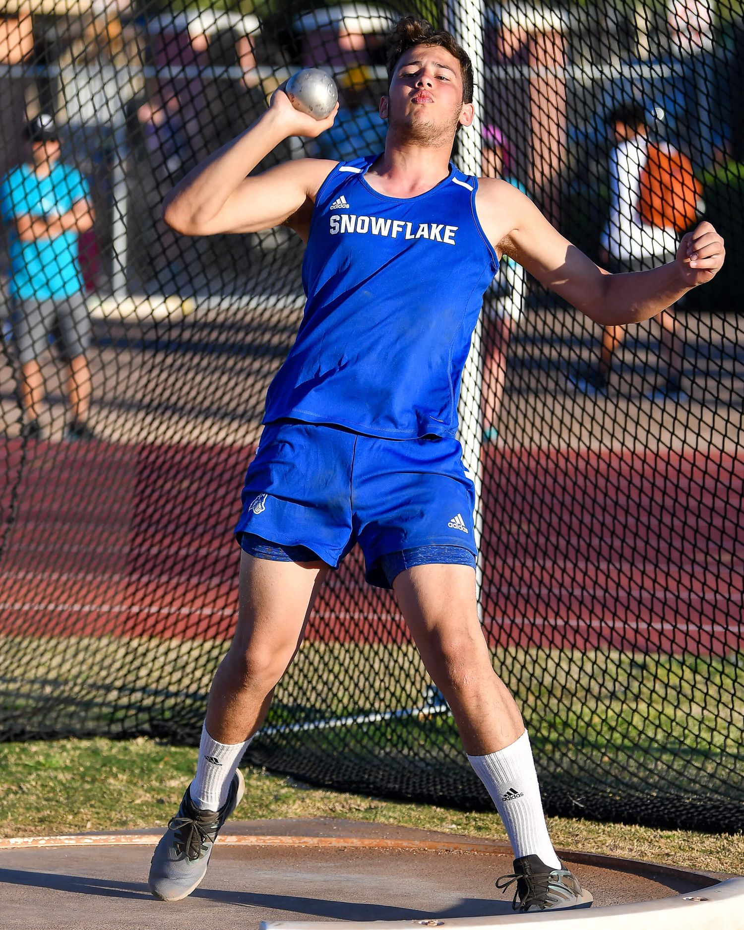 Snowflake athlete competes in discus throw wearing blue jersey at track and field event.