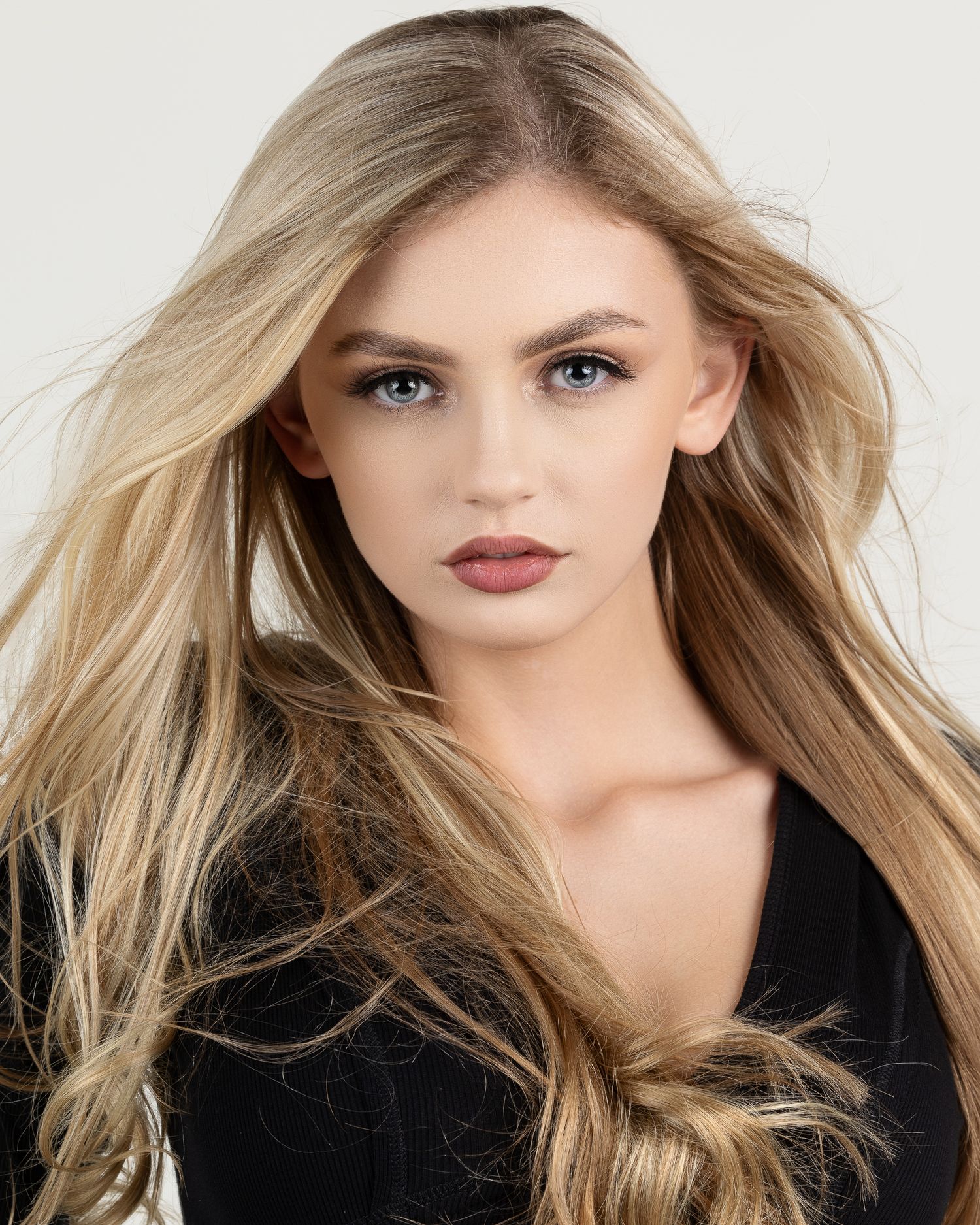 Beautiful blonde woman with blue eyes and long flowing hair in black top.