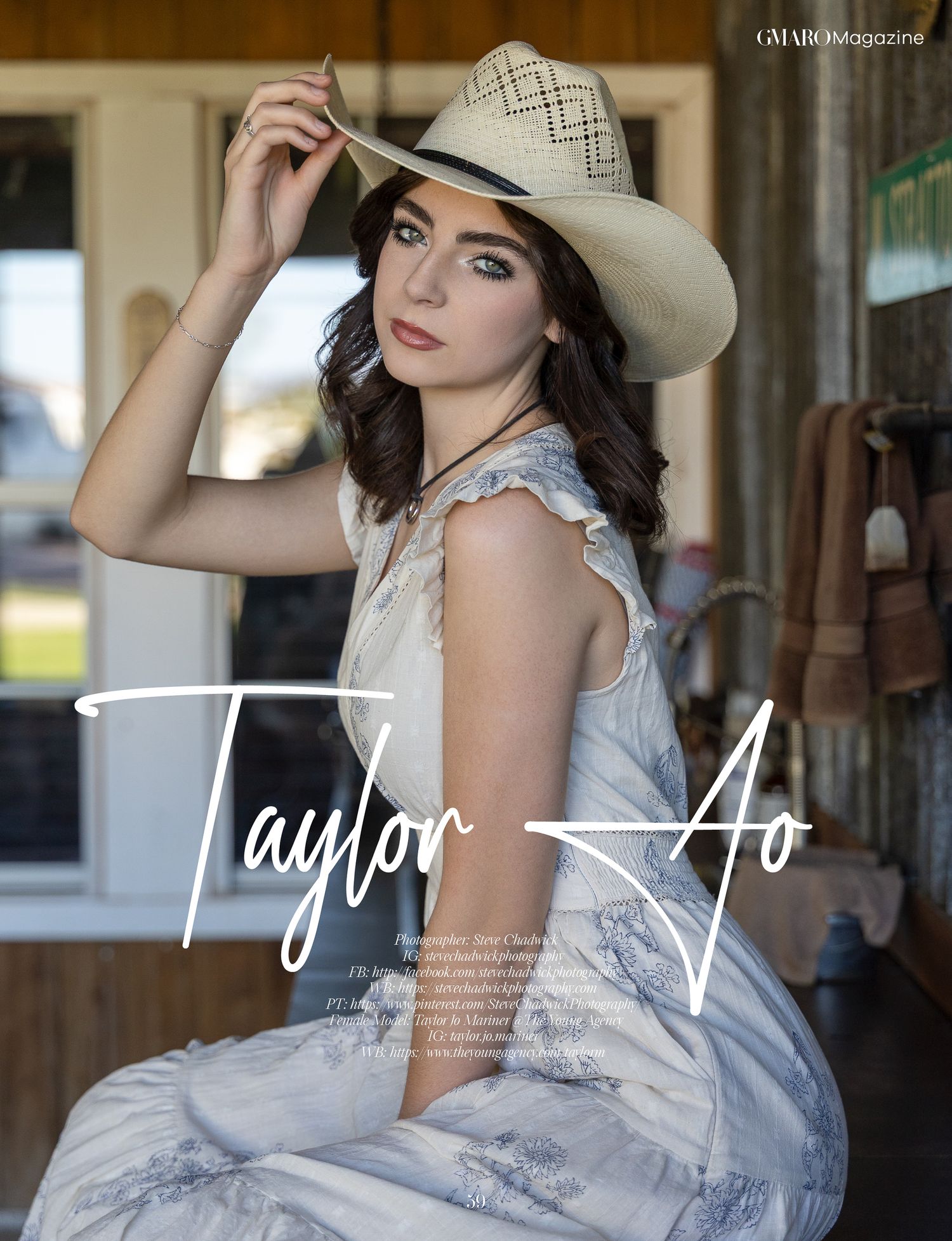 Young brunette model Taylor Ao poses in a white dress and cowboy hat in a rustic outdoor setting.