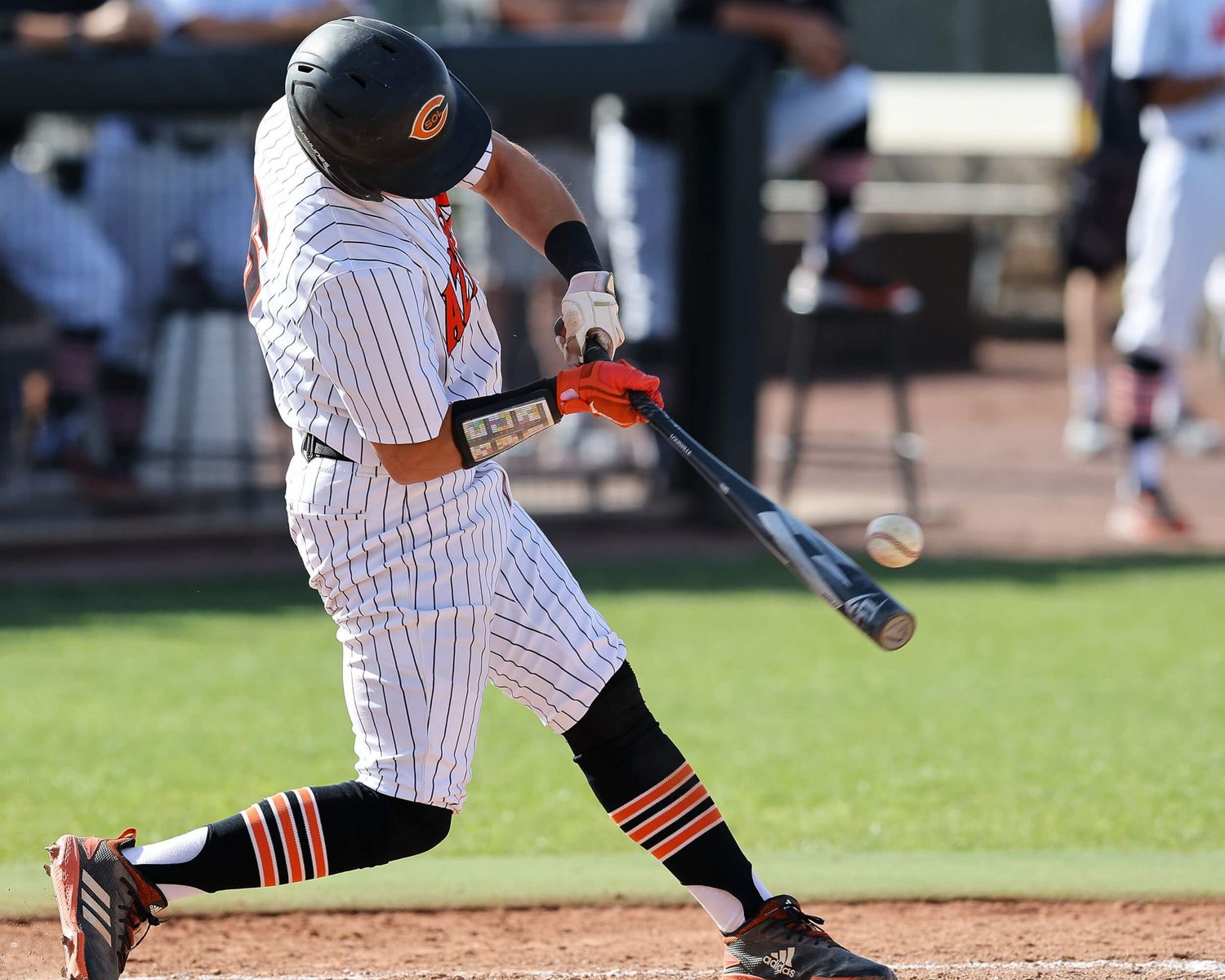 Baseball batter in white pinstripe uniform swings at a pitch during a game.