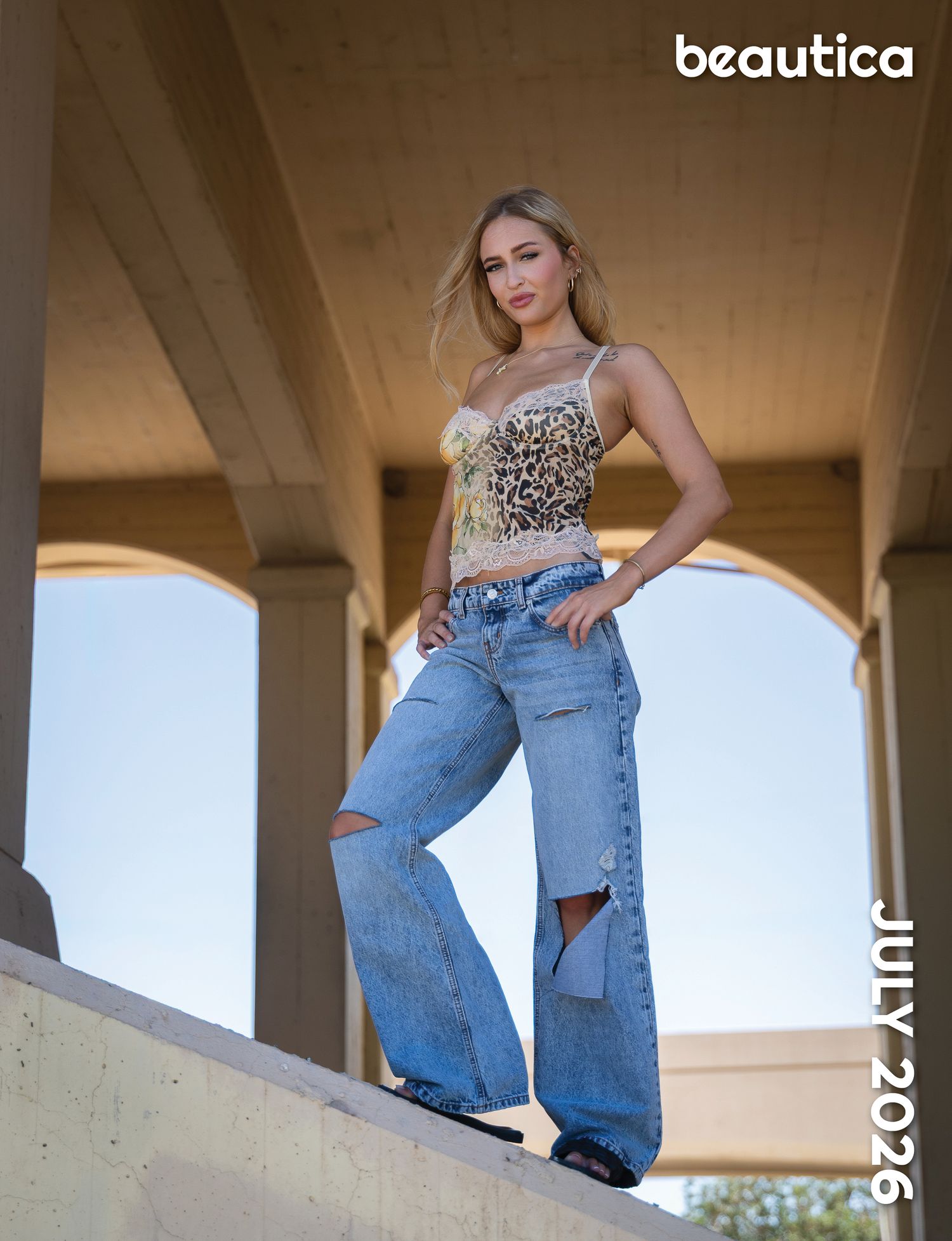 Blonde woman poses in ripped wide-leg jeans and leopard print top for Beautica July 2026 fashion editorial.