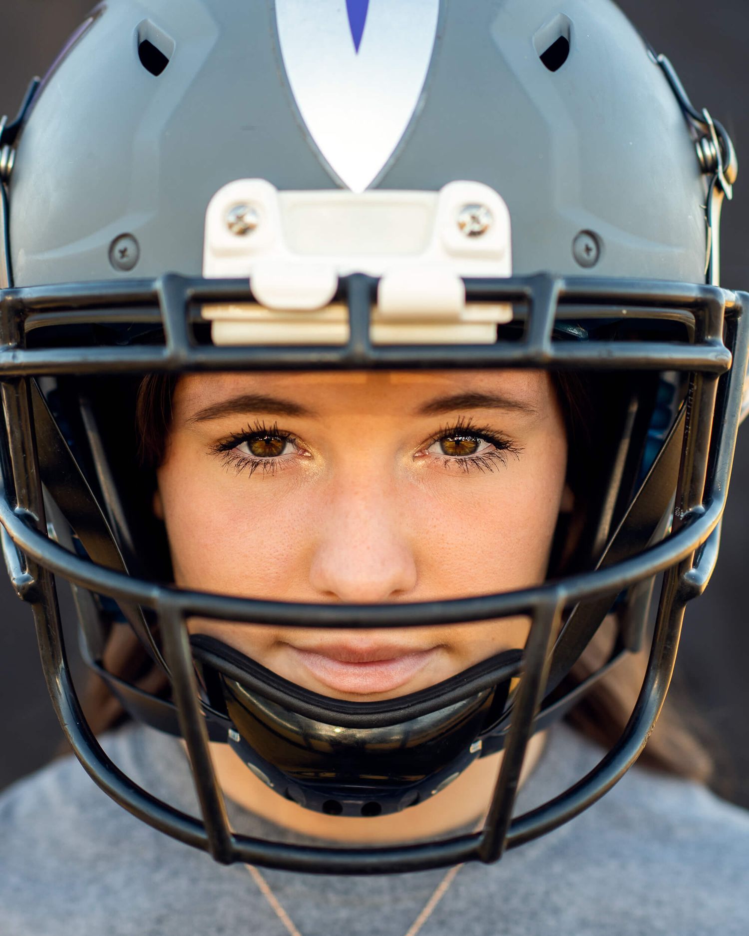 Close-up of a young athlete wearing a gray football helmet with face mask for a sports portrait.
