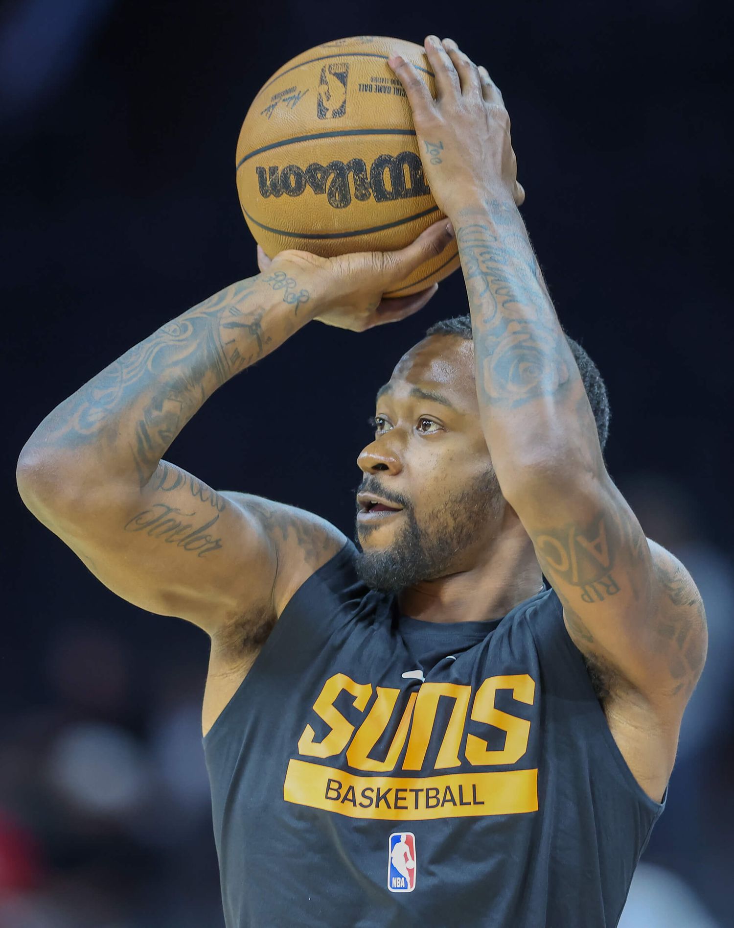 Phoenix Suns basketball player shooting a Wilson NBA ball during warm-ups wearing a gray Suns Basketball jersey.