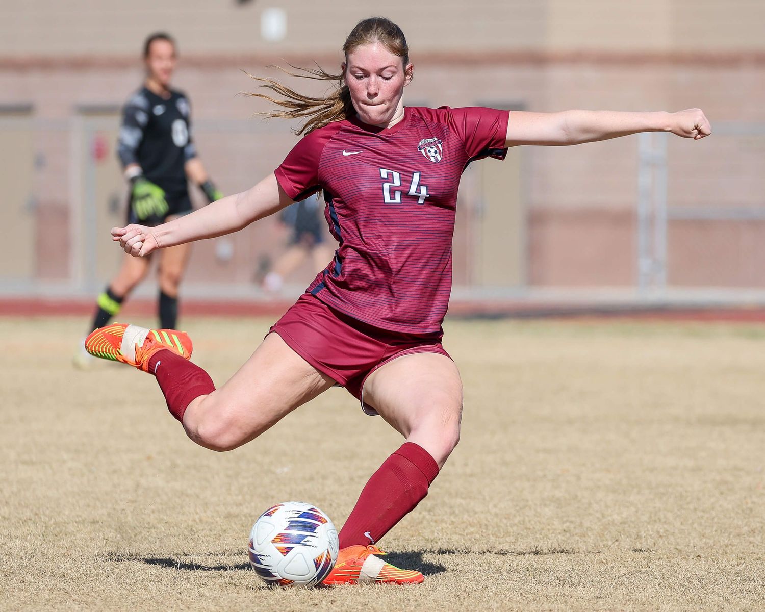 Female soccer player #24 in red uniform prepares to kick the ball during game.