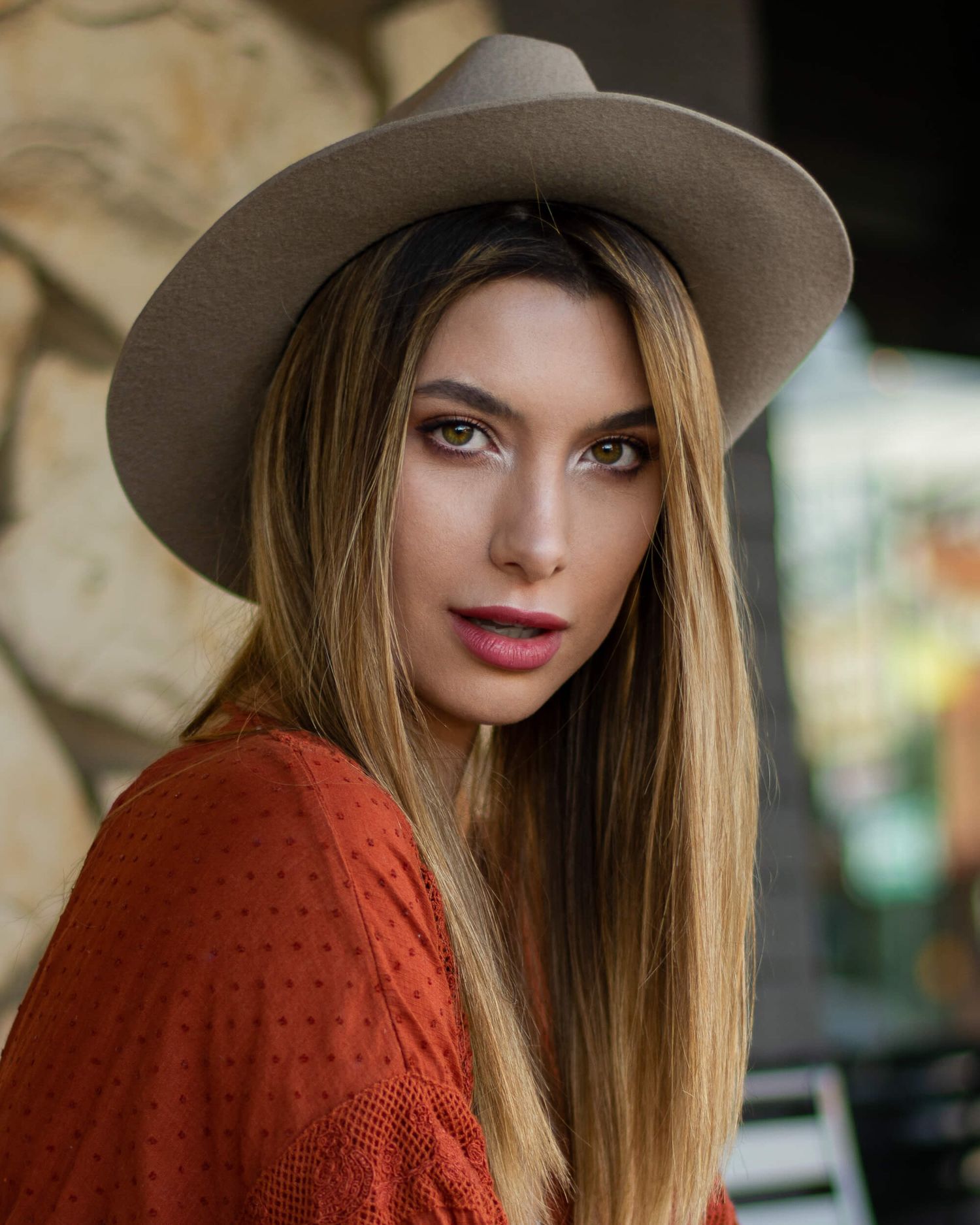 Close-up portrait of blonde woman in wide-brim hat and red sweater.