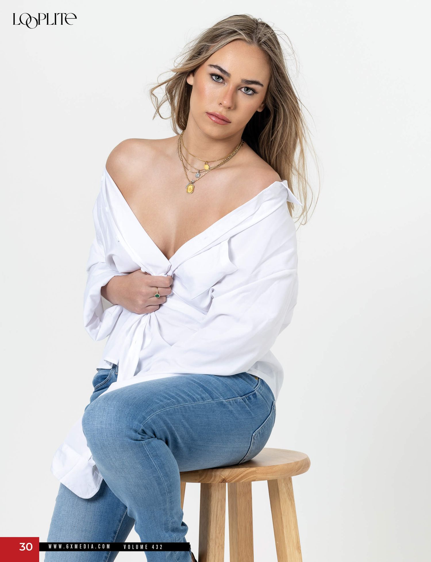 Blonde model in white off-shoulder shirt and blue jeans sits on stool for Losplite Magazine volume 422.