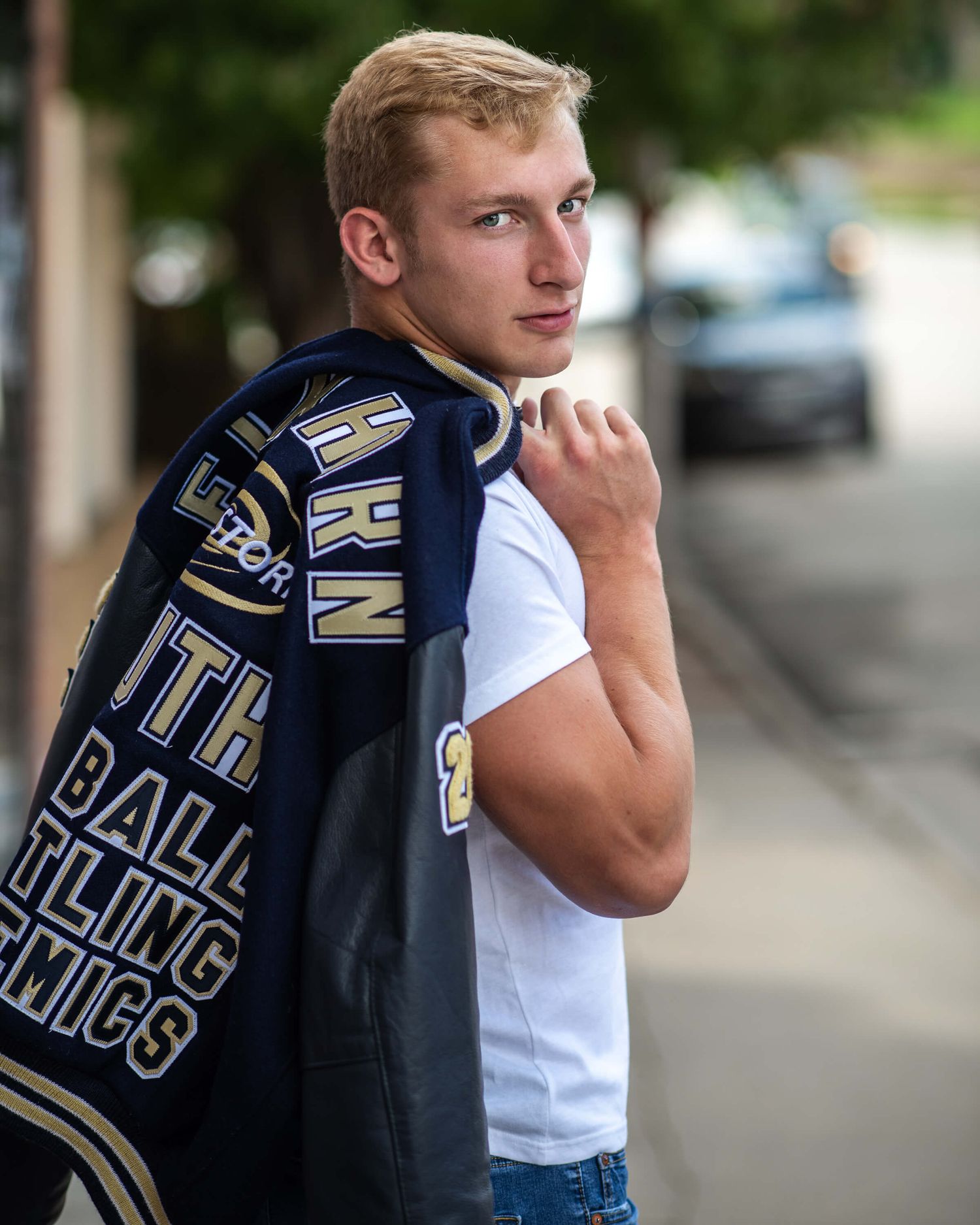 a high school senior portrait of a male holding his Leatherman jacket