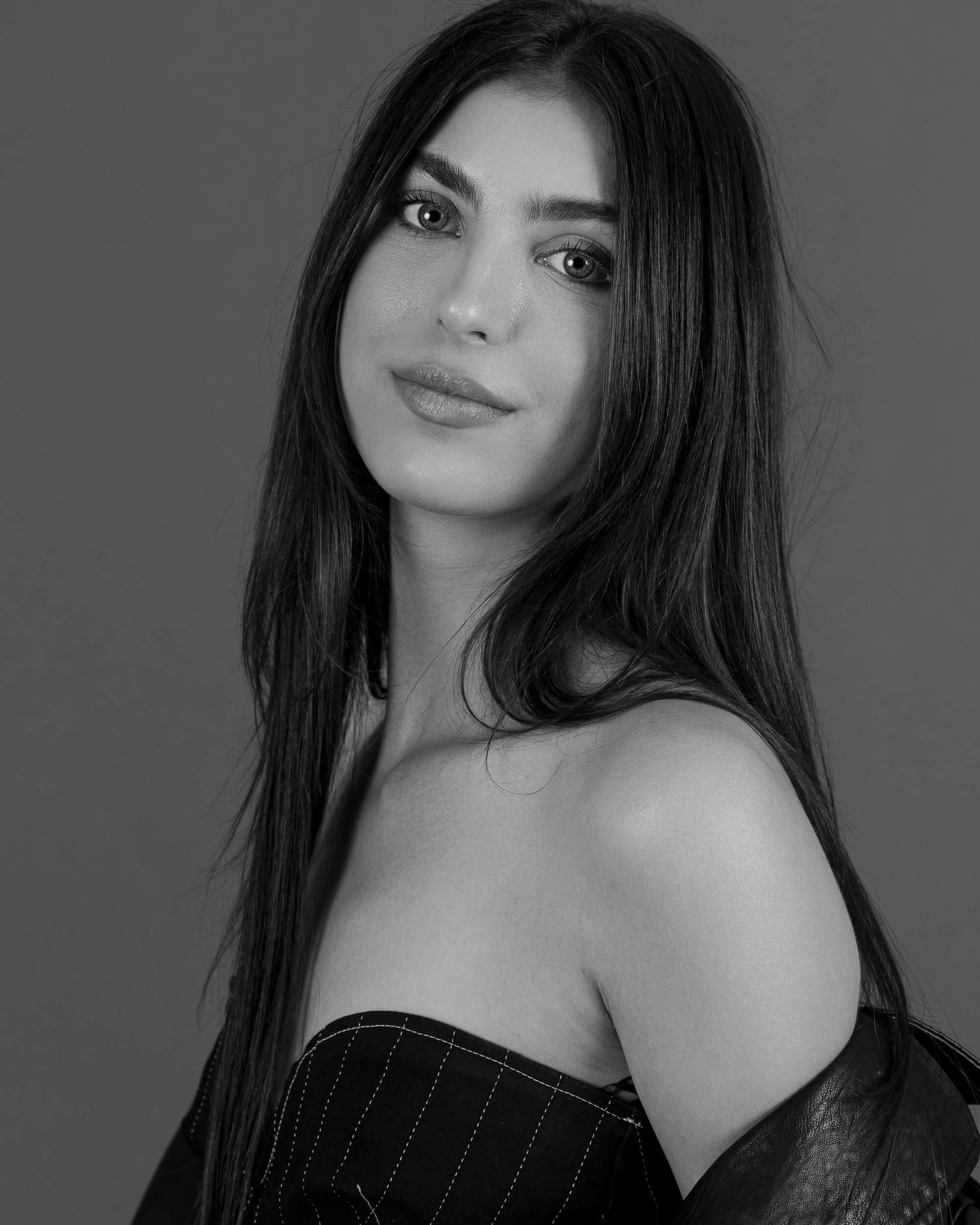 Black and white professional headshot of a young woman with long dark hair in a strapless top.