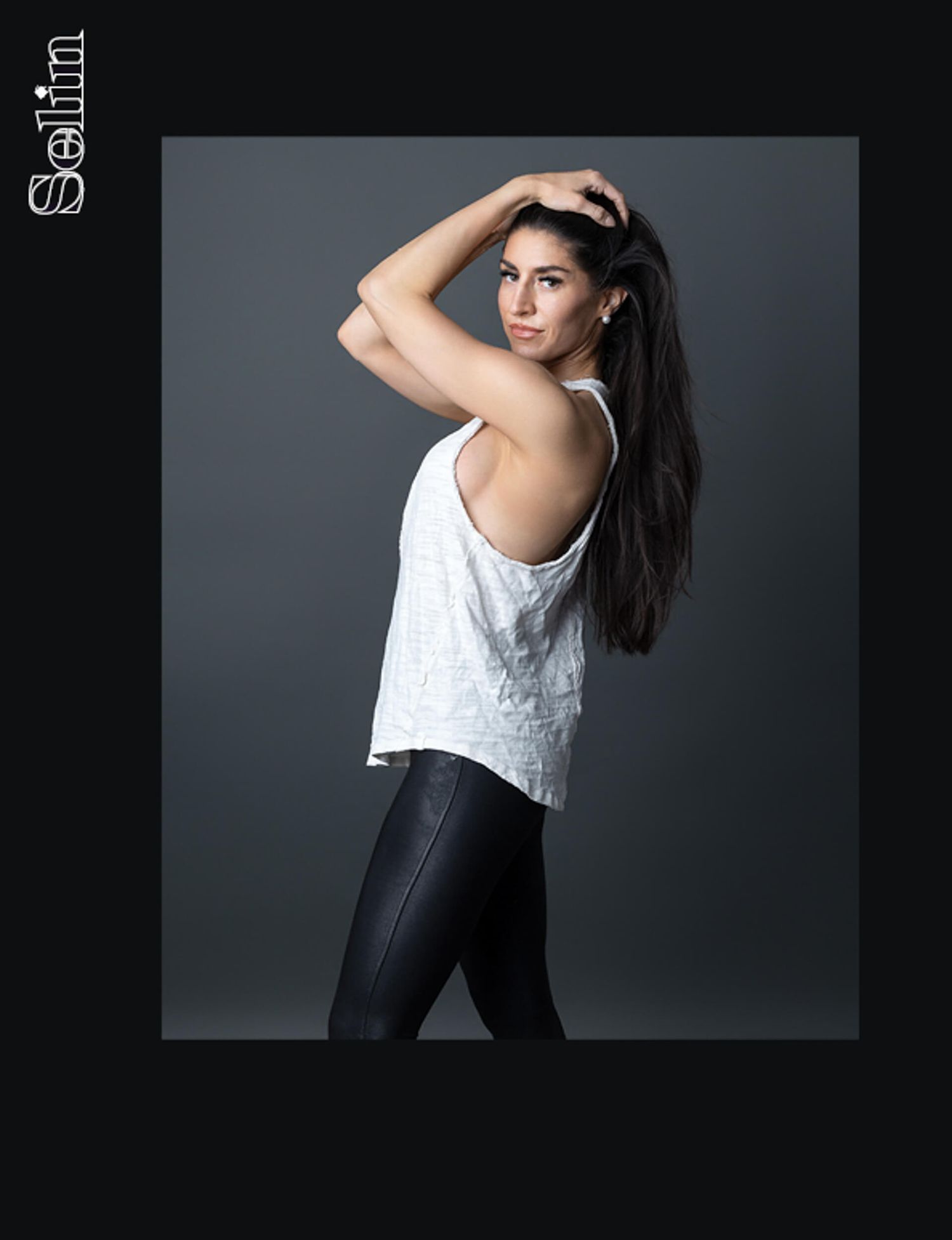 Dark-haired model in white backless top and black leather leggings poses for Solilim magazine.