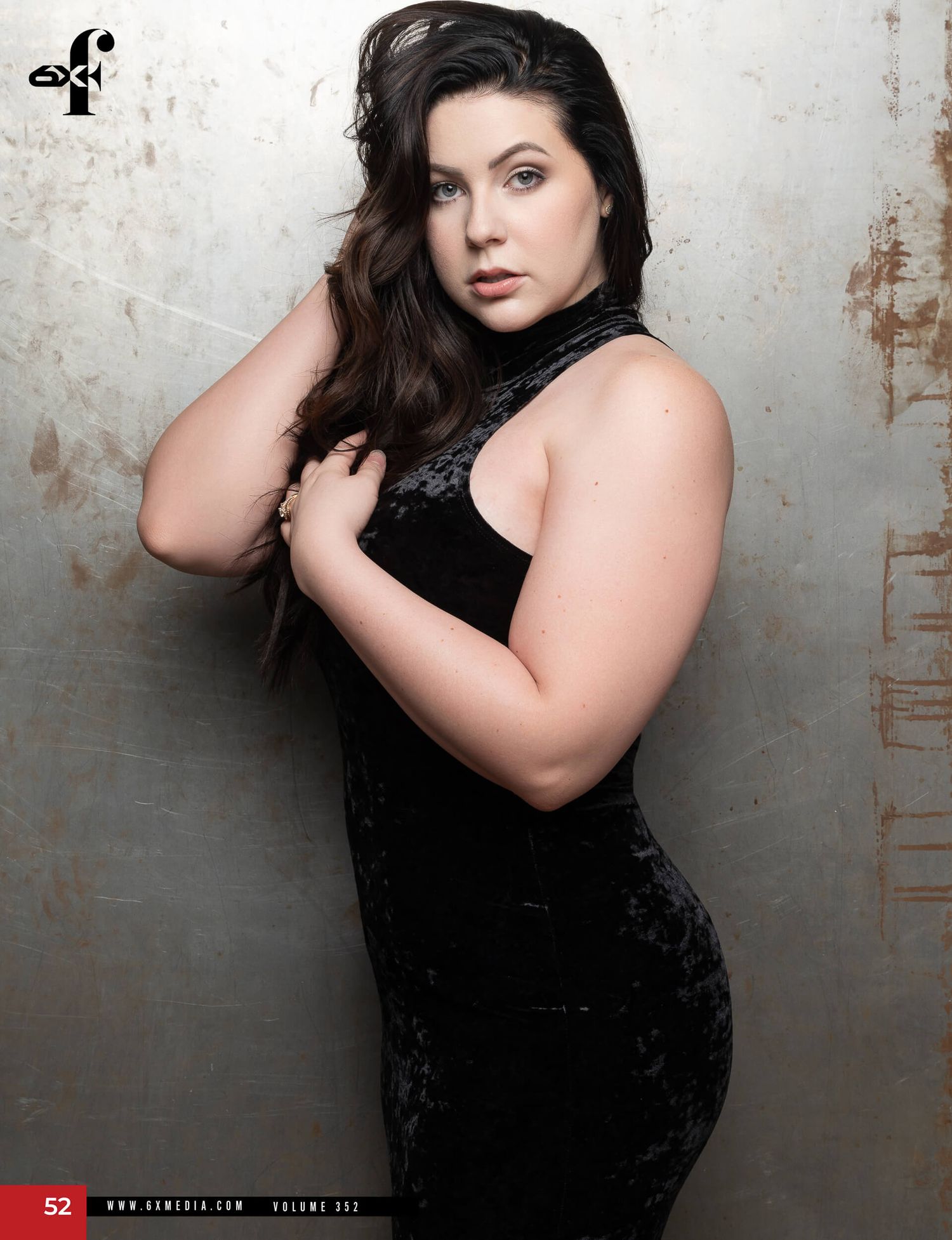 Brunette woman in black velvet dress posing for a fashion magazine editorial shoot.