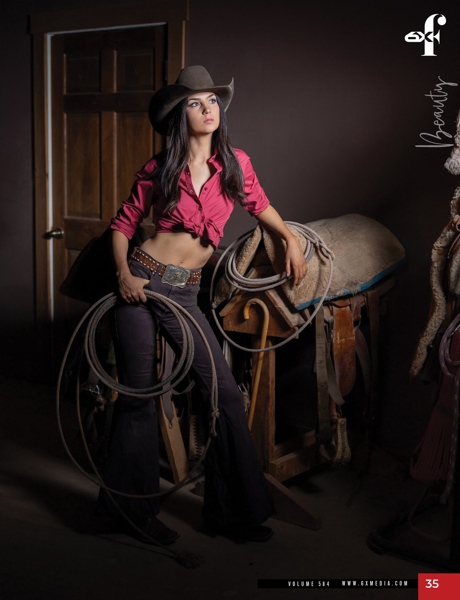 Female model in pink shirt and cowboy hat poses with a lasso in a western-themed magazine shoot.