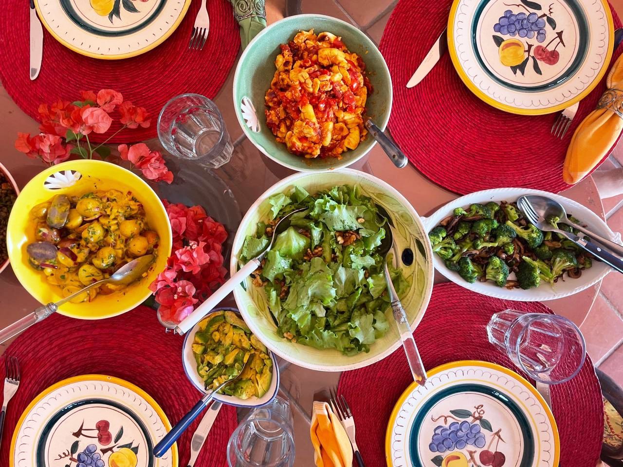 Overhead view of a vibrant dinner table with colorful dishes including salads and curries on decorative plates.