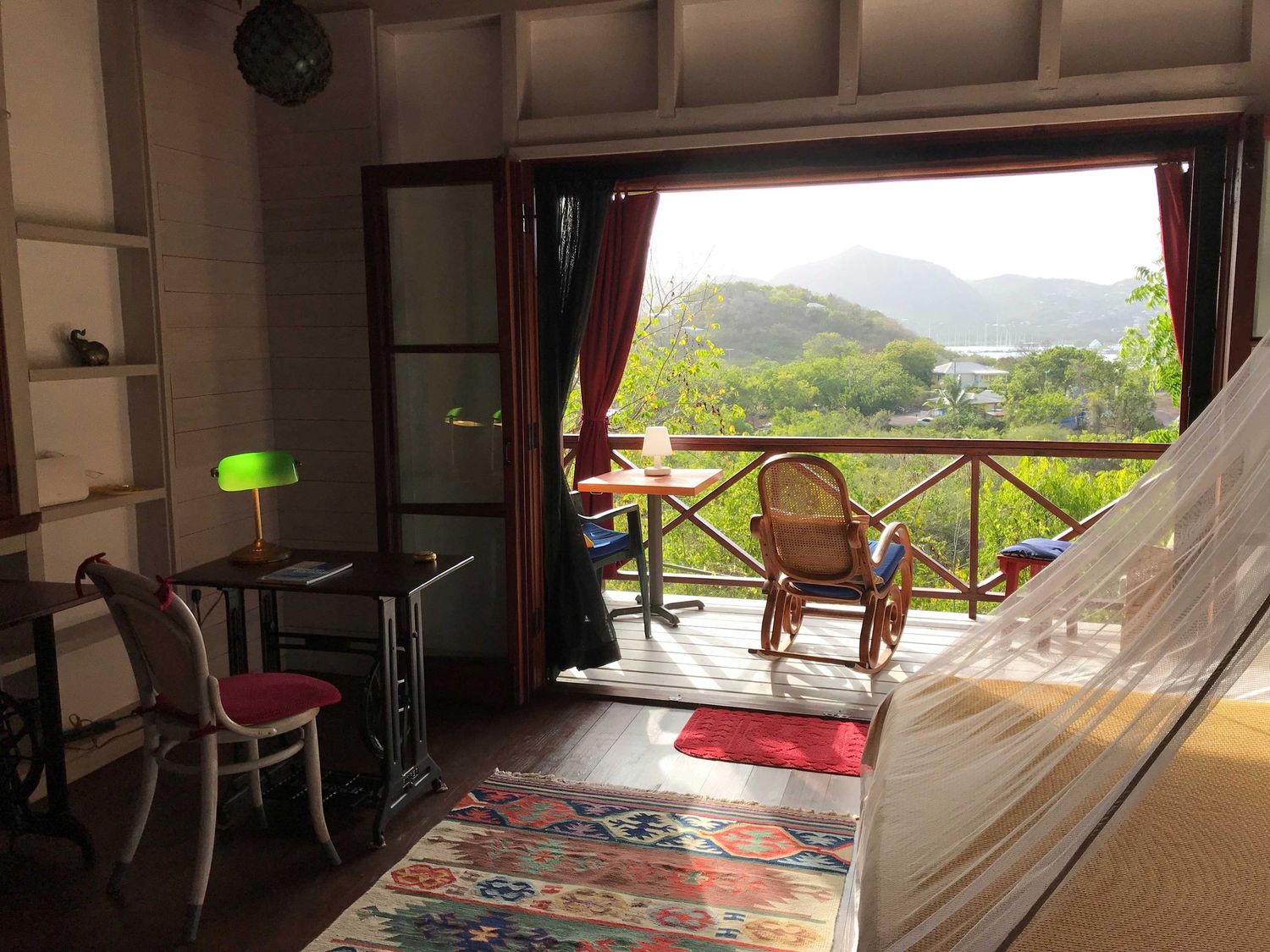 Cozy room interior with hammock, dining table, and open balcony offering scenic mountain views.