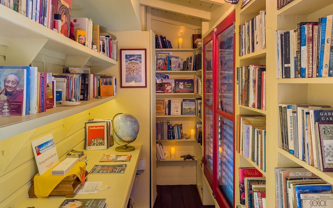 Cozy home library with floor-to-ceiling bookshelves, a globe, warm lighting, and a red glass cabinet filled with books.