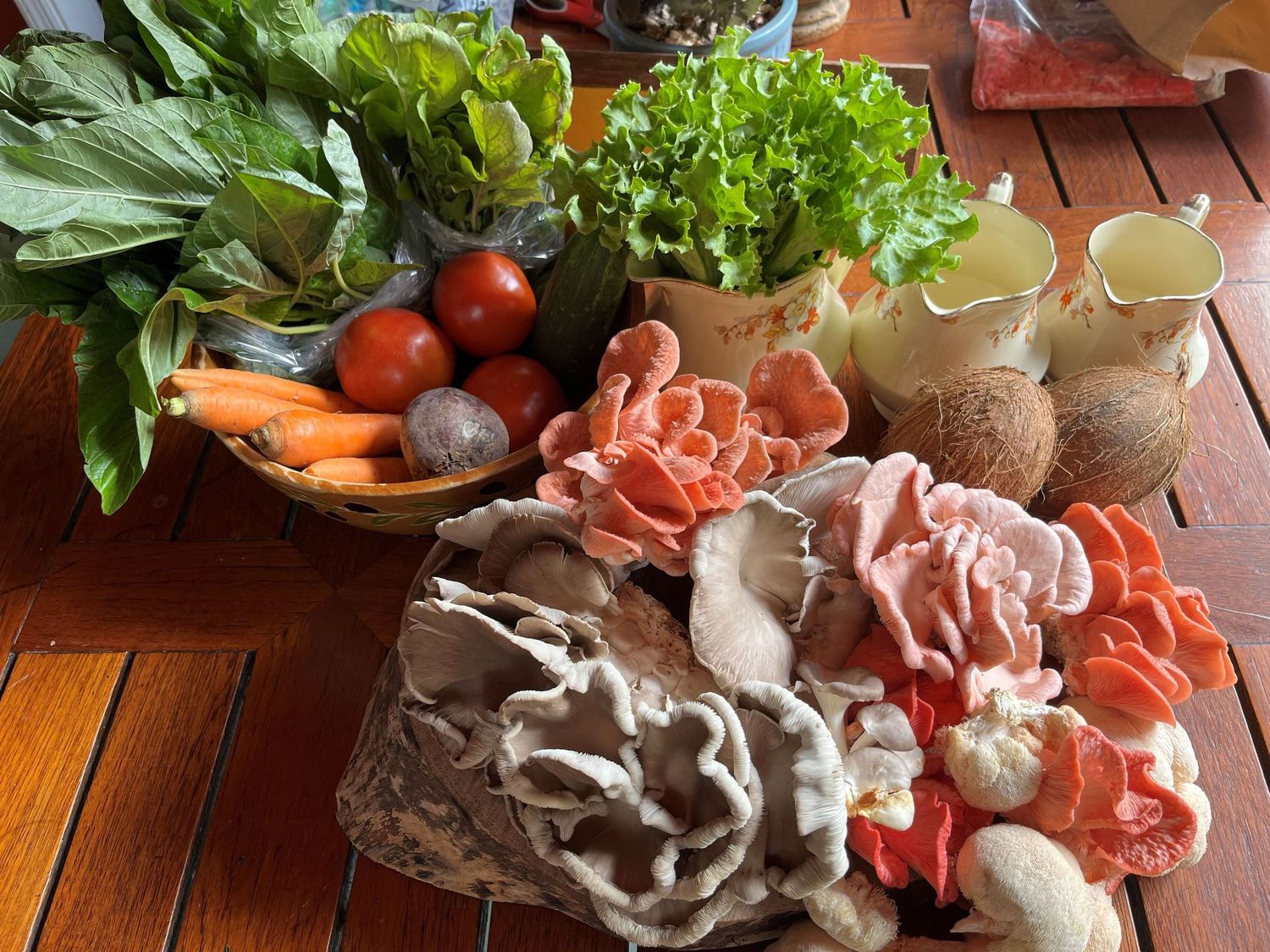 Fresh vegetables, mushrooms, and sliced meat arranged on a wooden table for hot pot cooking.