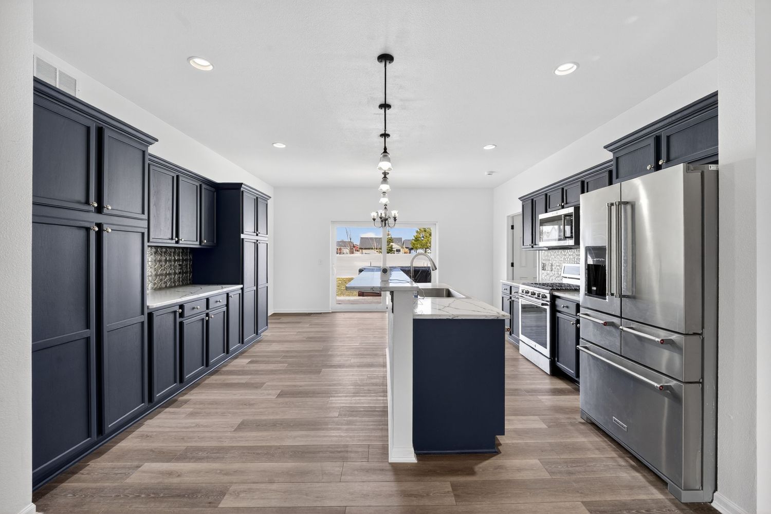 Modern kitchen with navy blue cabinets, stainless steel appliances, and center island.