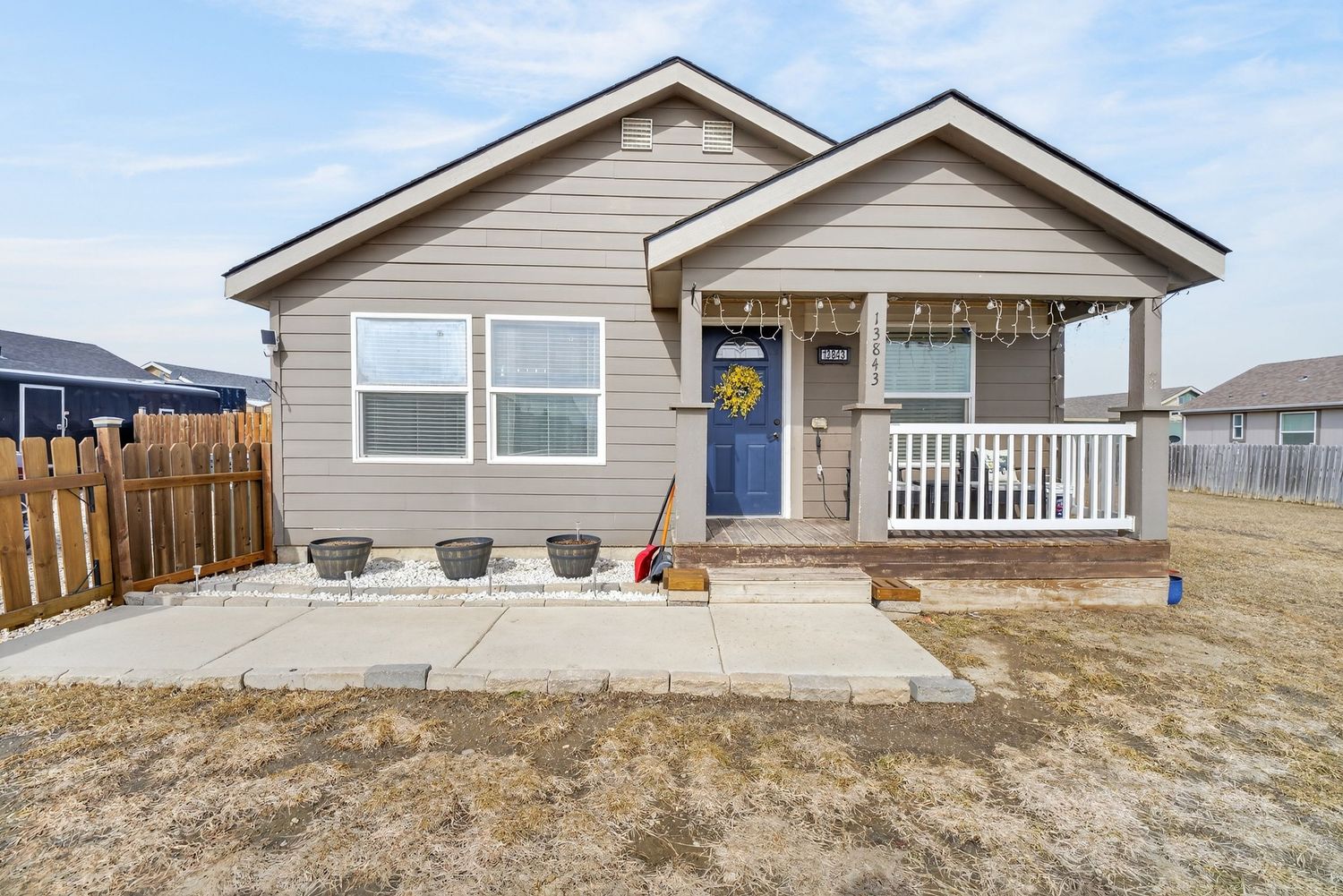 Charming bungalow exterior with covered porch, blue front door, and concrete walkway.