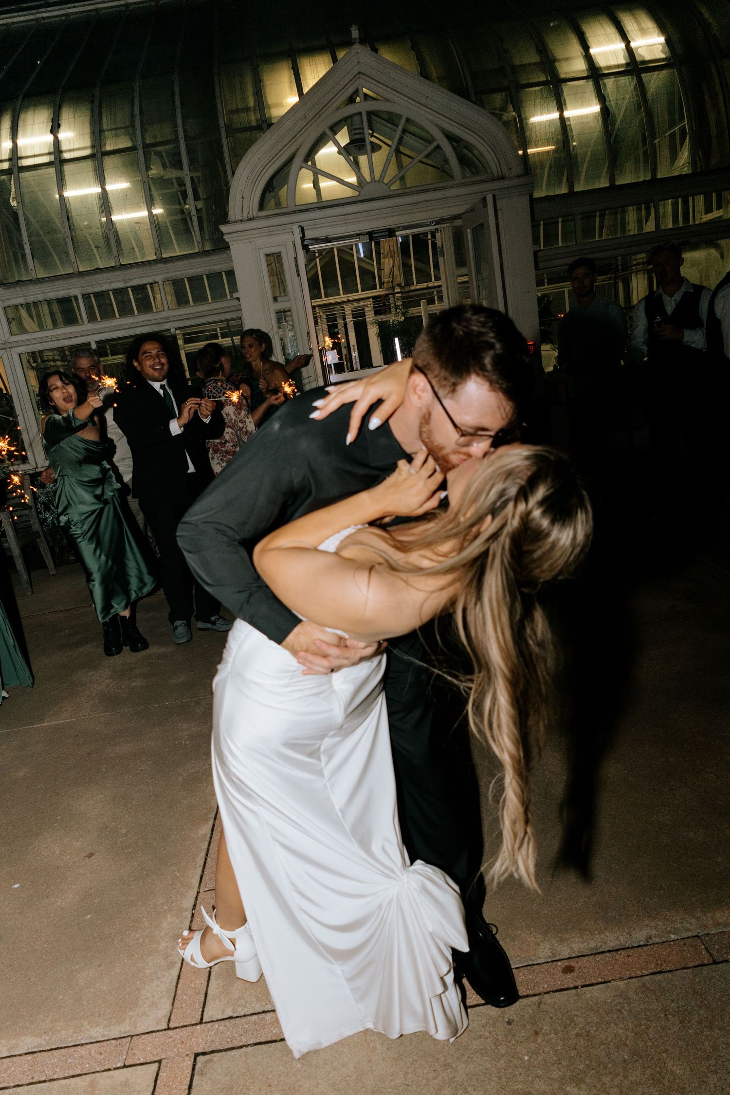 Bride and groom share a romantic dip kiss on the dance floor at their elegant wedding reception.