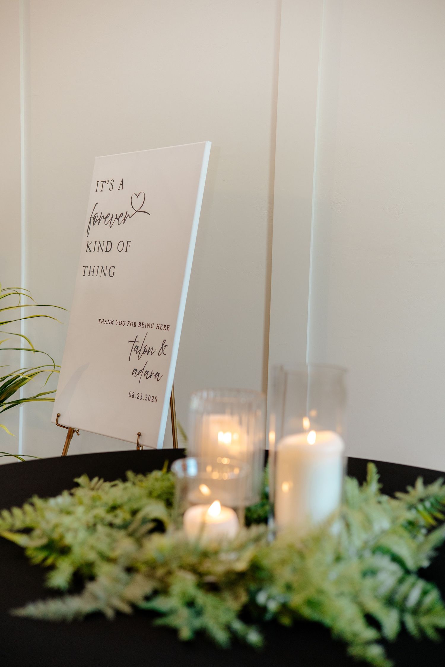 Elegant wedding sign reading it's a forever kind of thing with candles and greenery.