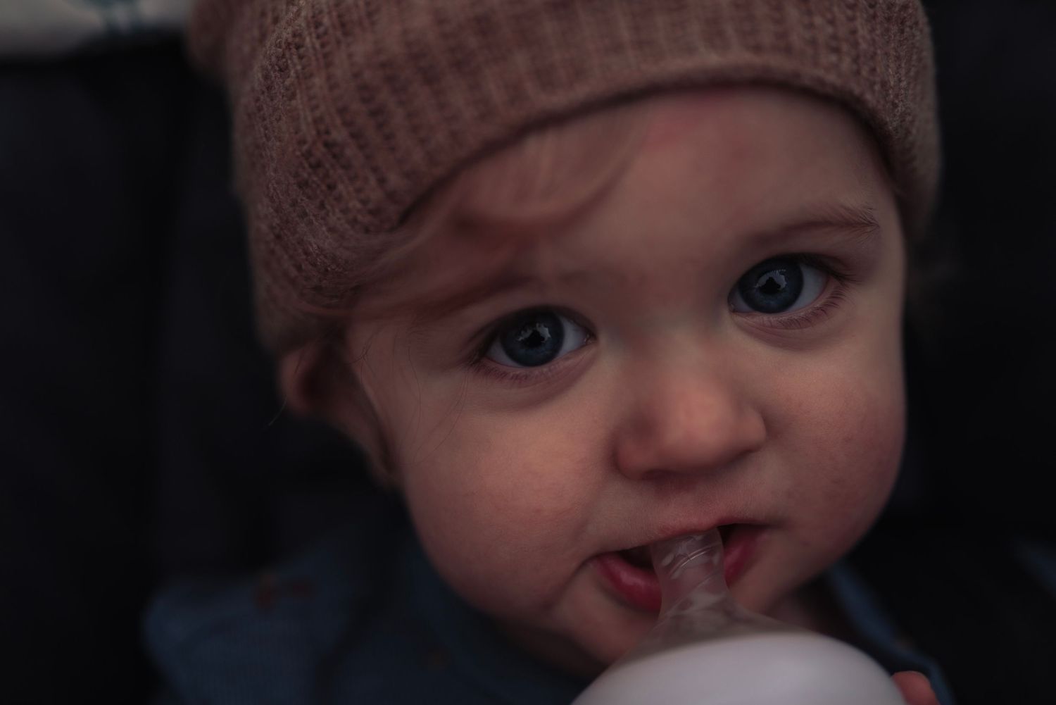 A cute baby with blue eyes wearing a knit beige hat during first birthday session, Neo Ohio, outdoors, family.