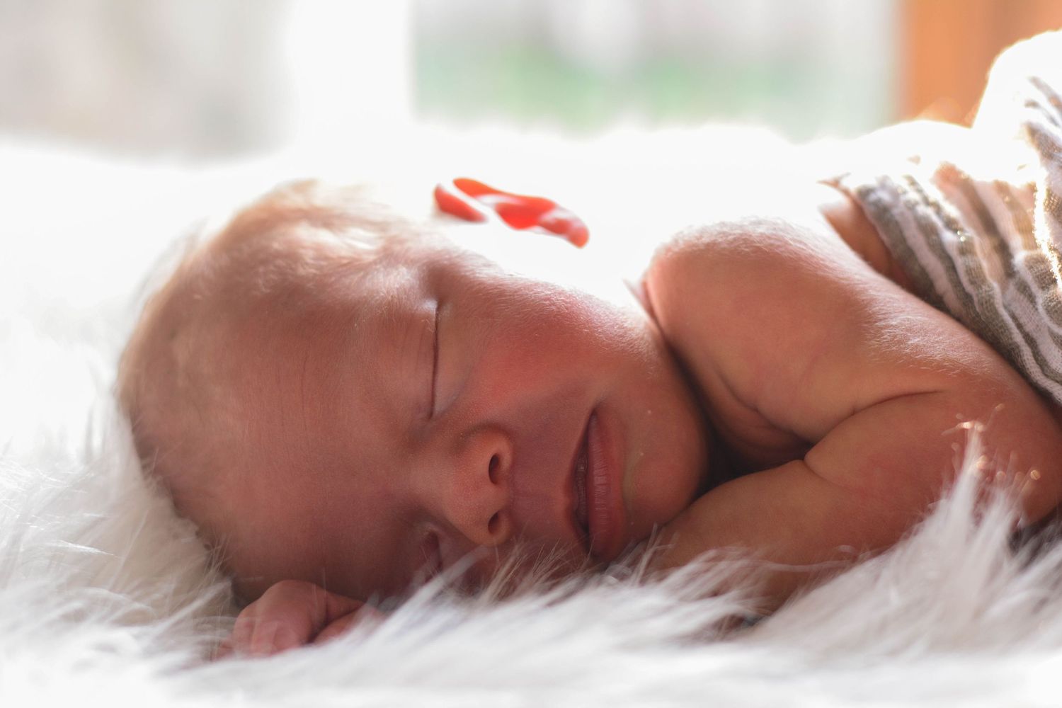 Cozy indoor newborn photography featuring a close-up of a sleeping baby wrapped in a soft blanket during a lifestyle photo shoot.