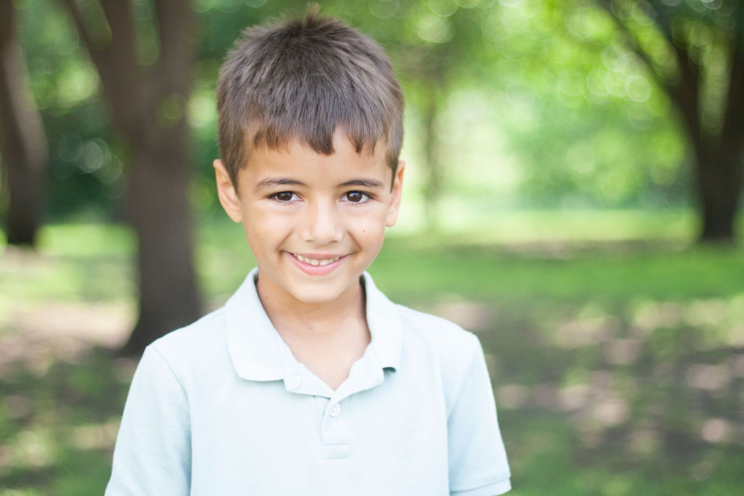 Vibrant outdoor children's photography of a young boy smiling warmly during a family photo shoot at Chisholm Trail Park in Plano, Texas.