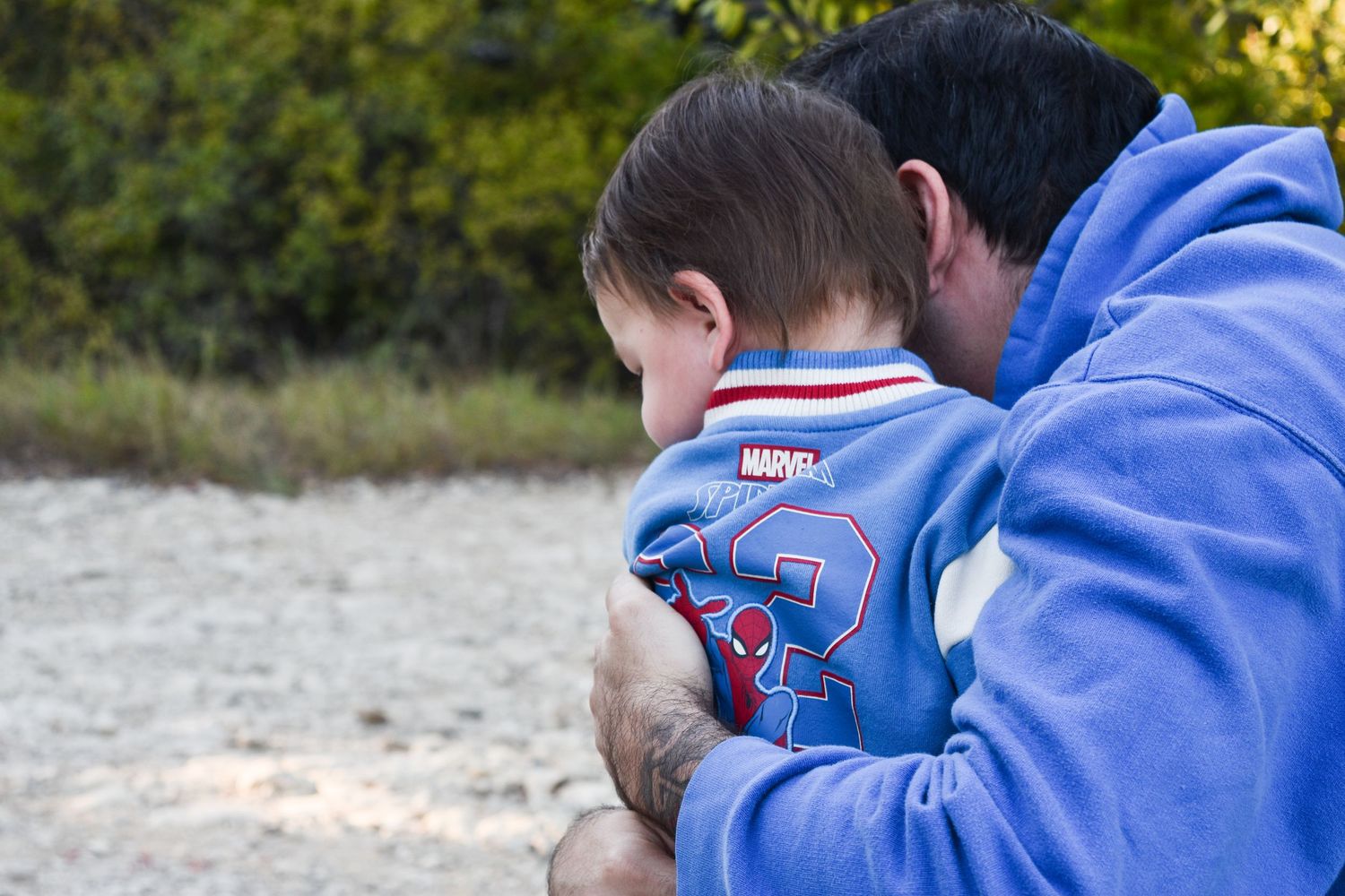 Vibrant family photography of a dad hugging his toddler at Arbor Hills Nature Preserve in Plano, Texas.