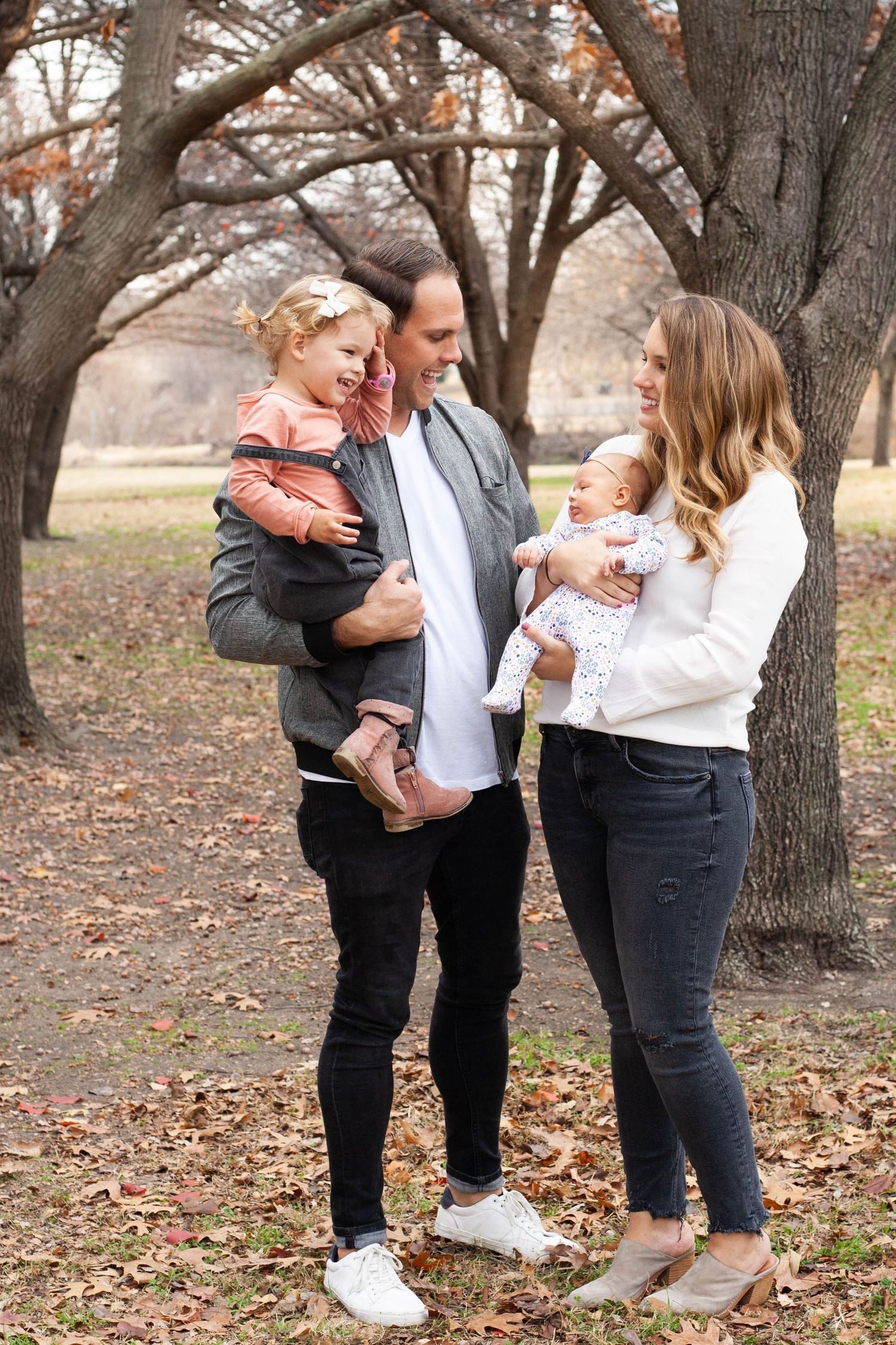 Vibrant outdoor family photography featuring parents with their toddler girl and newborn baby girl during a portrait session in North Dallas