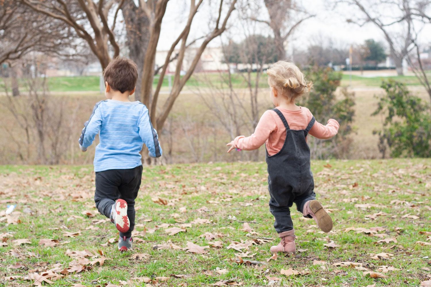 Vibrant outdoor children's photography of a toddler boy and girl running and playing together at Chisholm Trail Park in Plano, Texas.