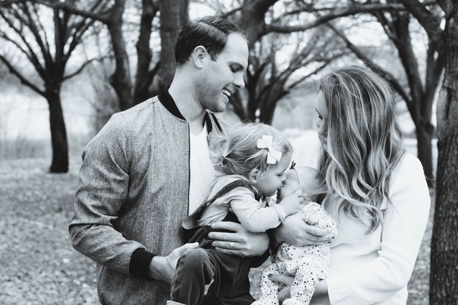 Vibrant outdoor family photography featuring parents with their toddler girl and newborn baby girl during a portrait session in North Dallas