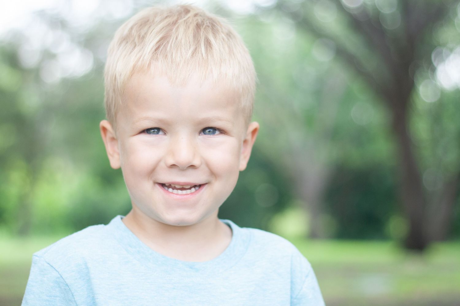 Vibrant outdoor children's photography of a young boy smiling warmly during a family photo shoot at Chisholm Trail Park in Plano, Texas.