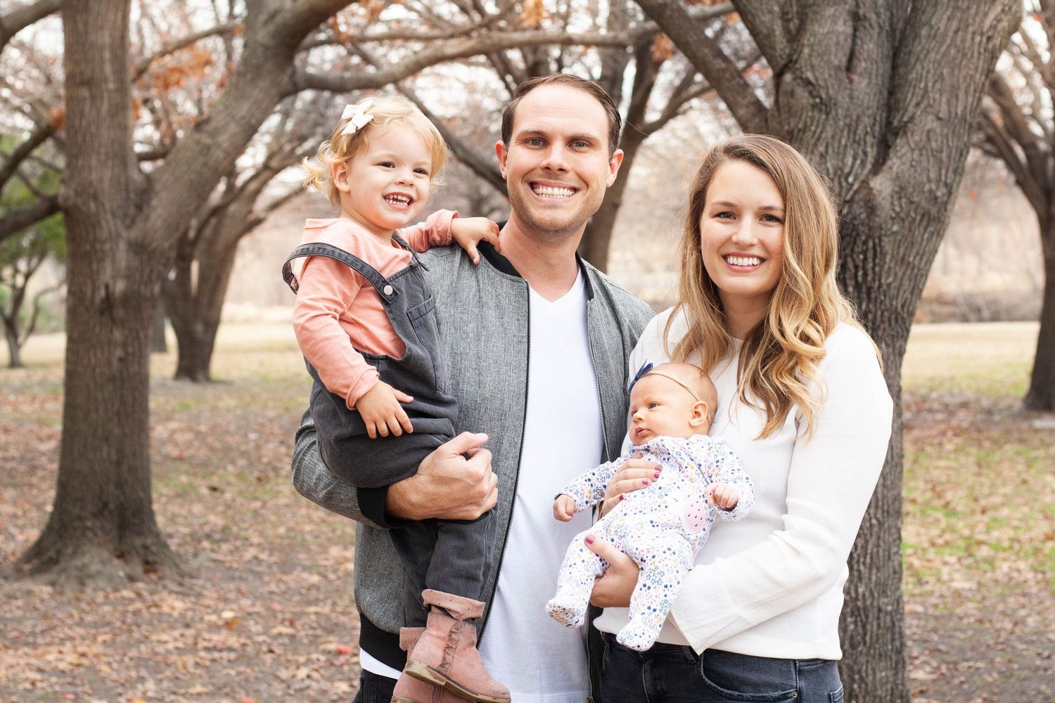 Vibrant outdoor family photography featuring parents with their toddler girl and newborn baby girl during a portrait session in North Dallas