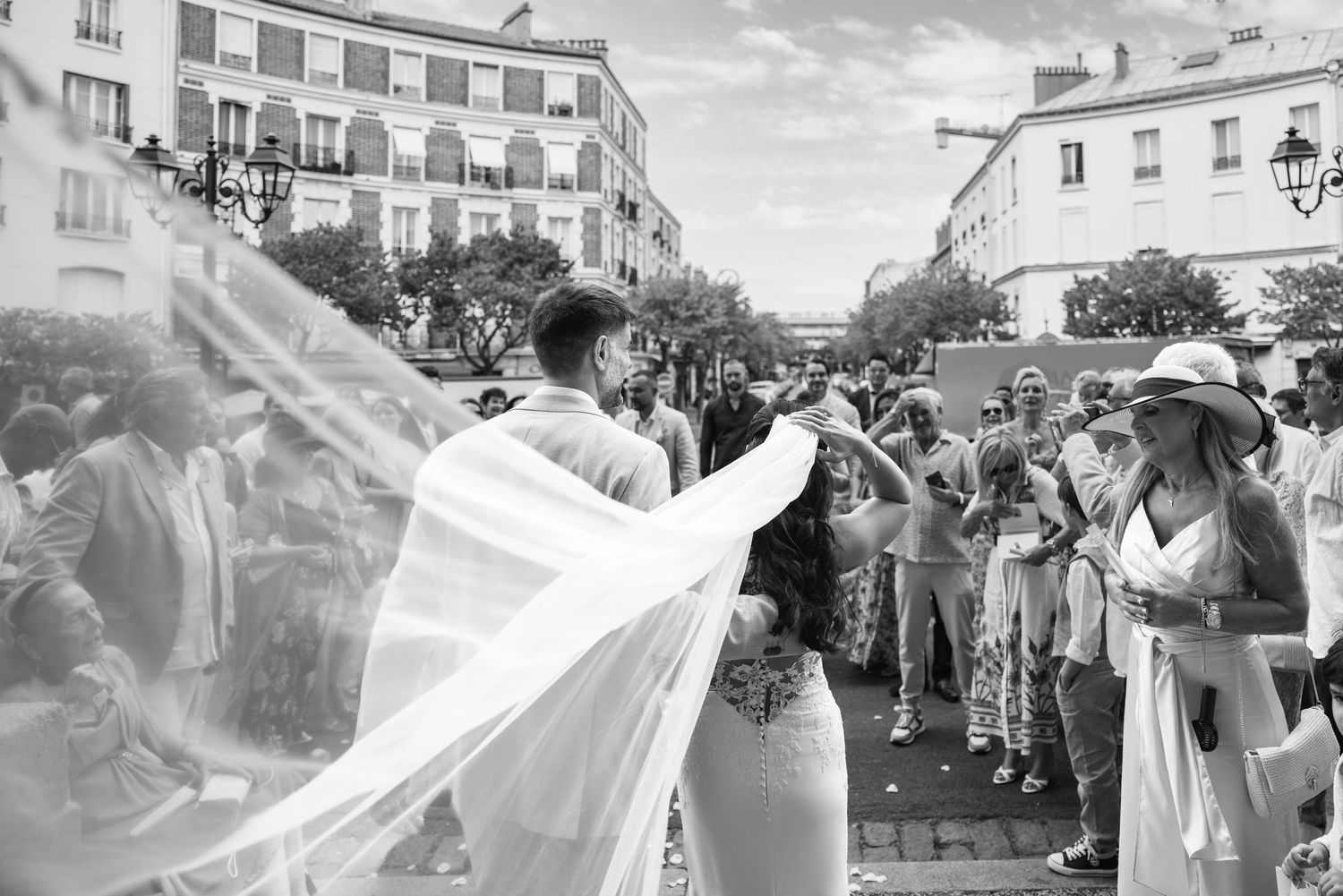 La robe de mariée flottante s'envole dans l'air alors que le couple accueille joyeusement les invités du mariage à l'extérieur