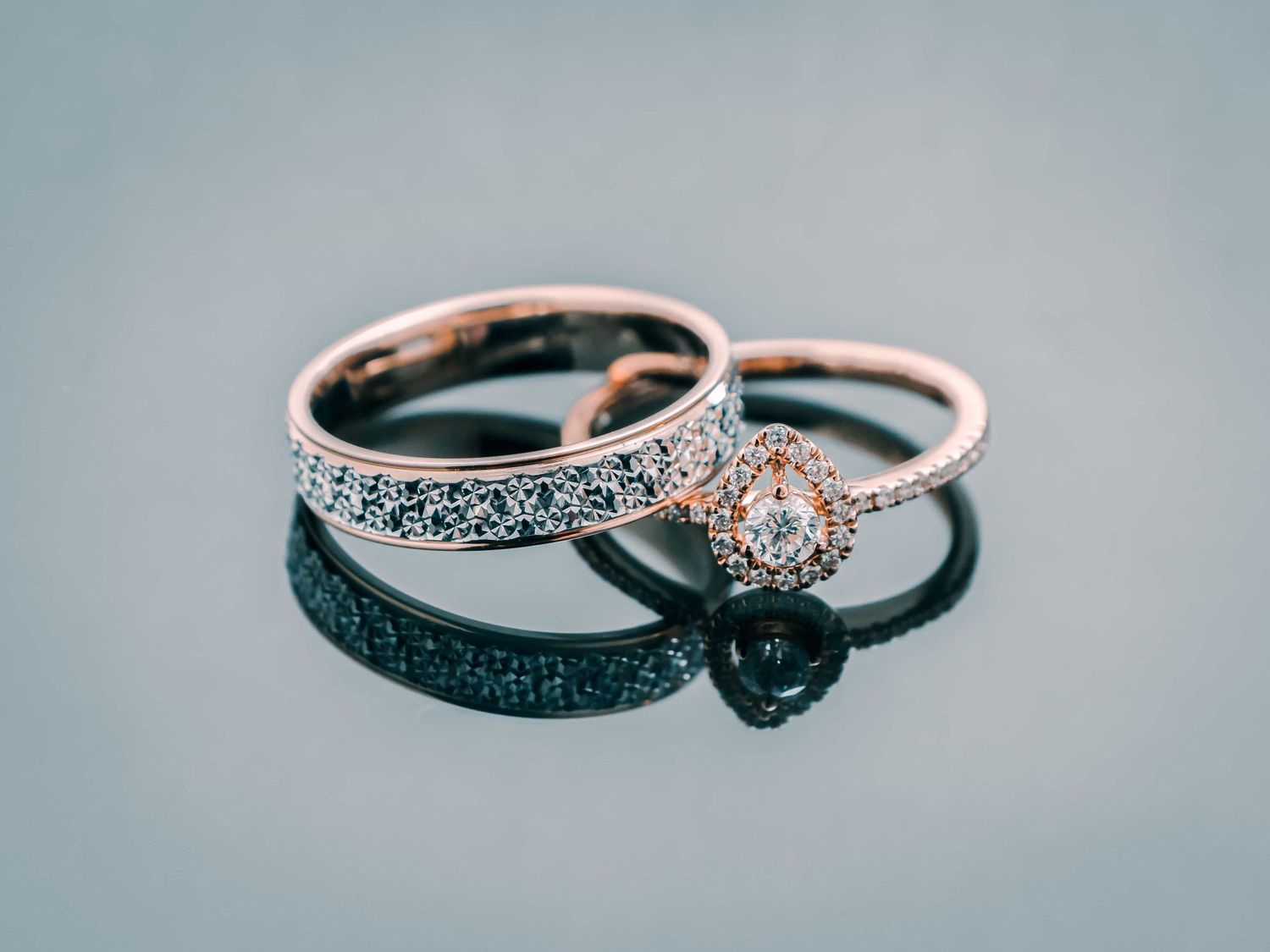 Alliance sertie de diamants et bague de fiançailles en or rose sur une surface réfléchissante.