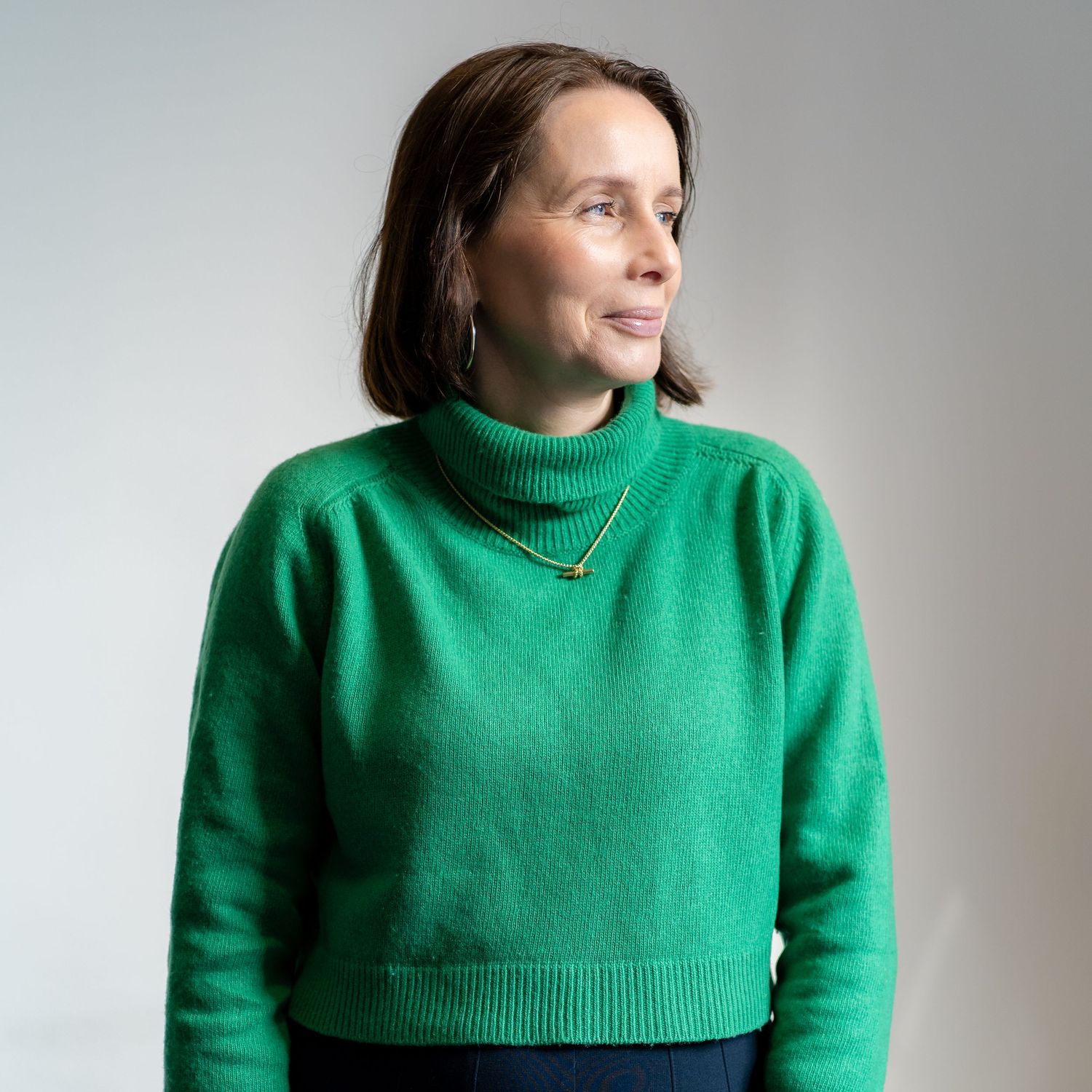 Portrait of person wearing bright green turtleneck sweater against white background.