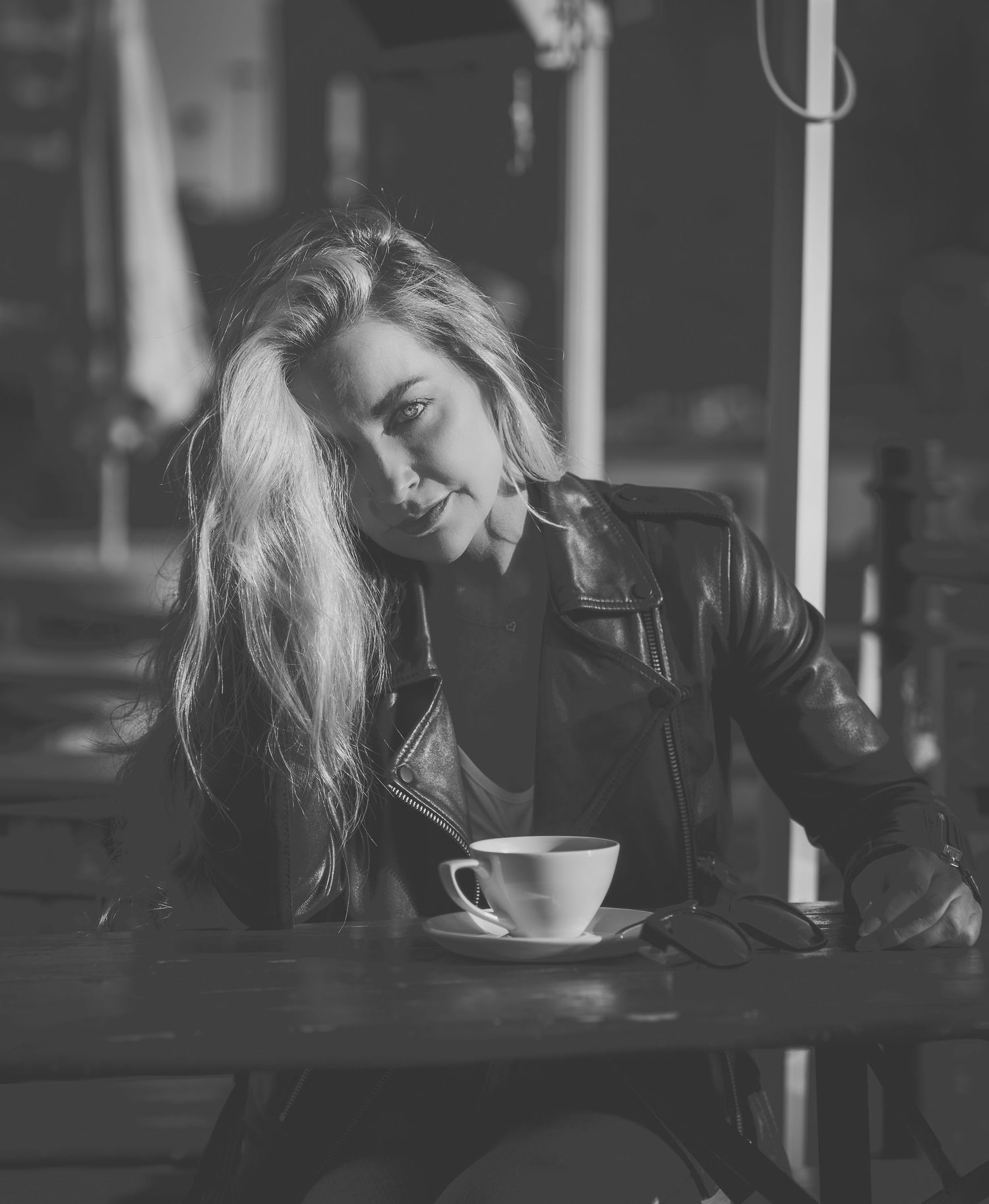 Artistic black and white portrait of person with blonde hair relaxing at cafe with coffee.