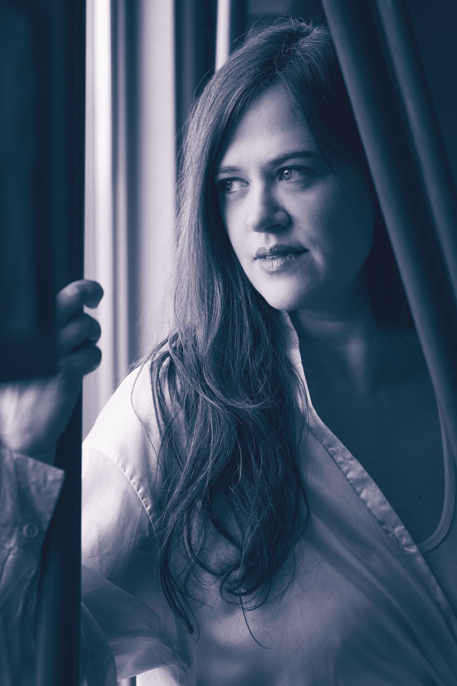 Moody portrait series by a window with dramatic lighting and deep shadows.