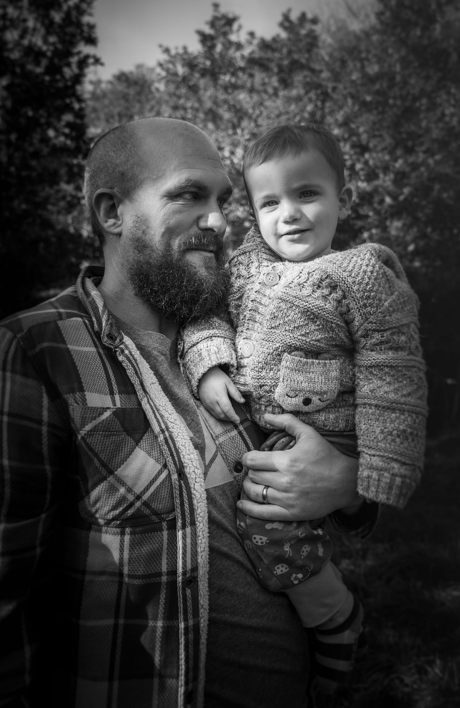 Tender black and white family moments captured between father and child in outdoor setting.