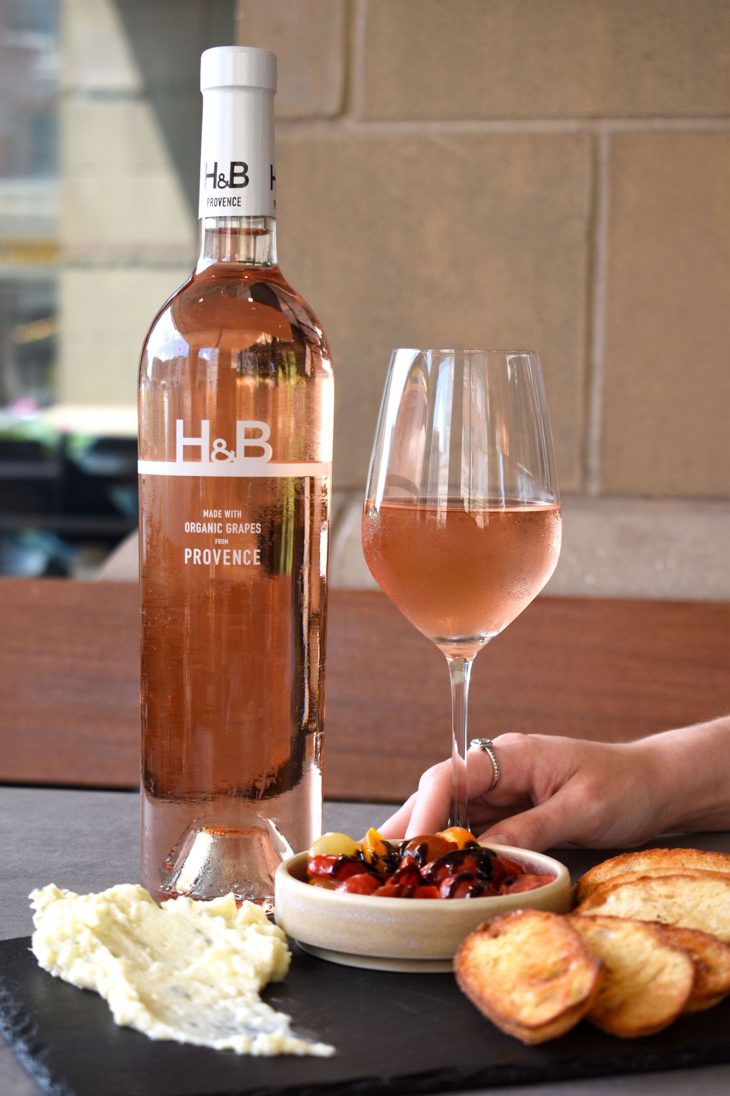 H&B Provence organic rosé wine bottle with glass and charcuterie board featuring bruschetta and cheese.