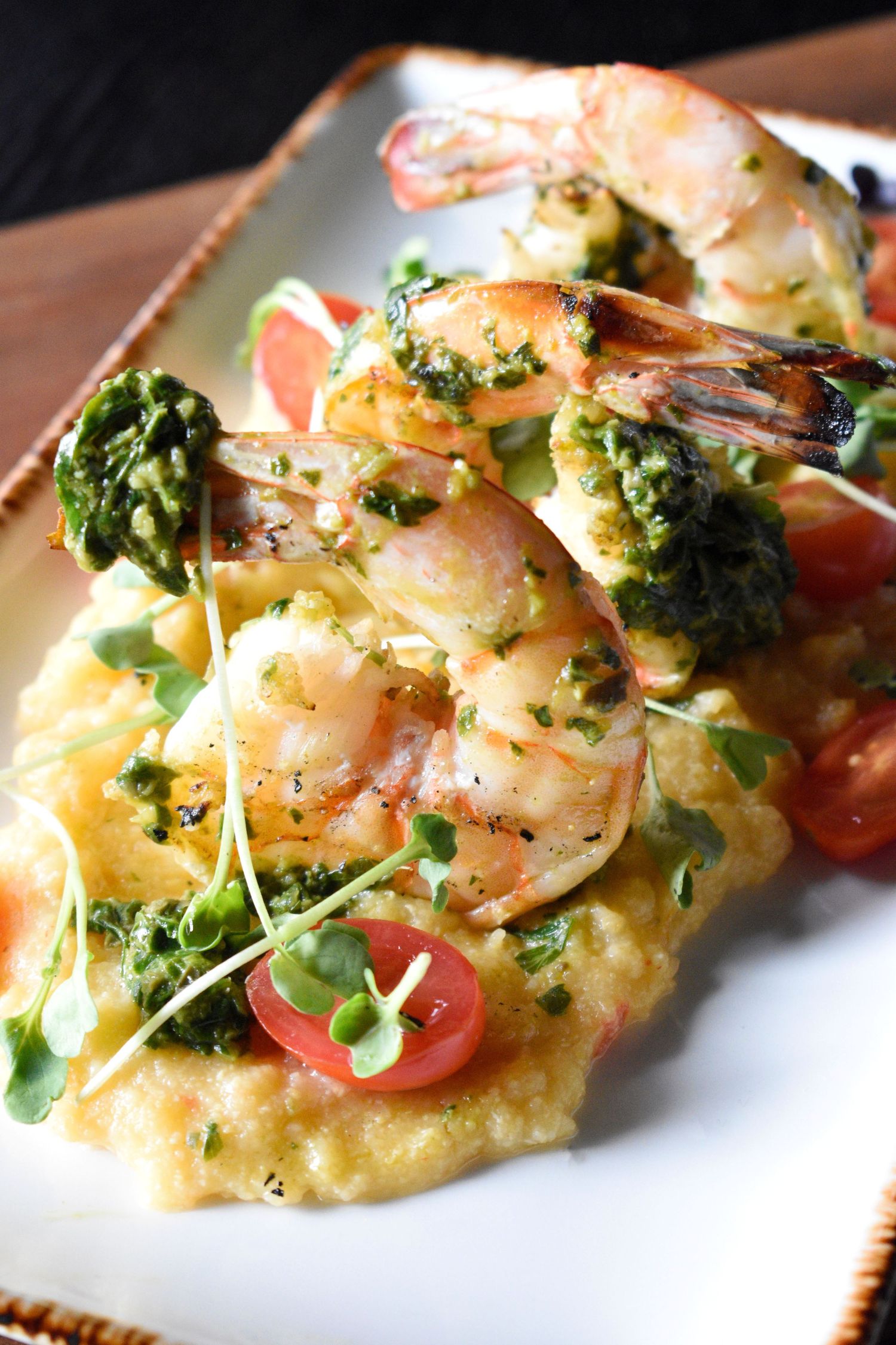 Grilled jumbo shrimp with chimichurri sauce served over creamy polenta with cherry tomatoes.