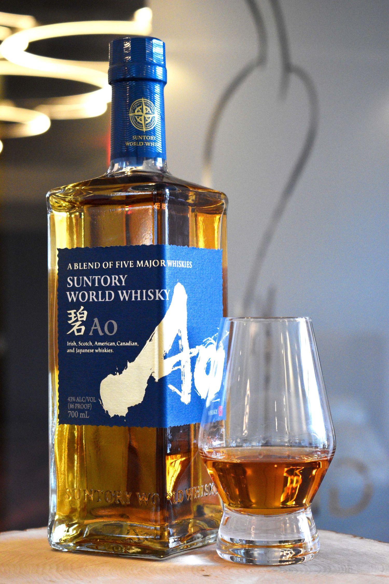 Suntory World Whisky Ao blend of five major whiskies bottle displayed beside a Glencairn glass of golden whisky.