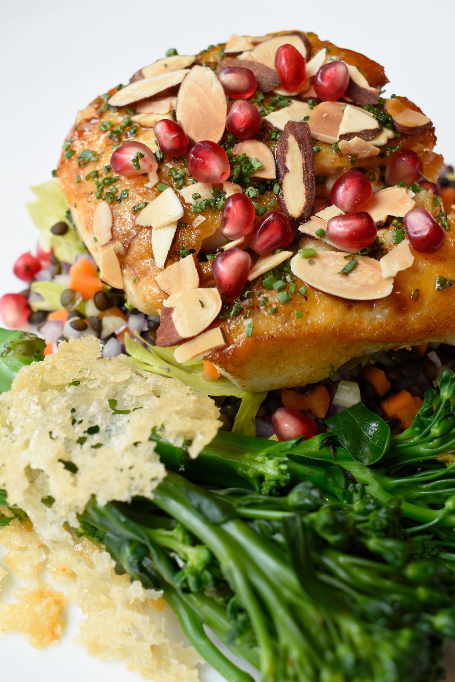 Roasted chicken breast topped with pomegranate seeds and sliced almonds served with broccolini and stuffing.