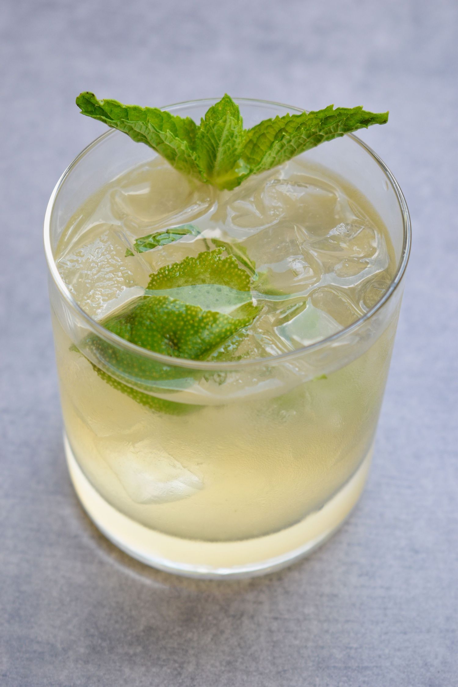 A refreshing iced cocktail with lime slices and fresh mint leaves in a rocks glass.