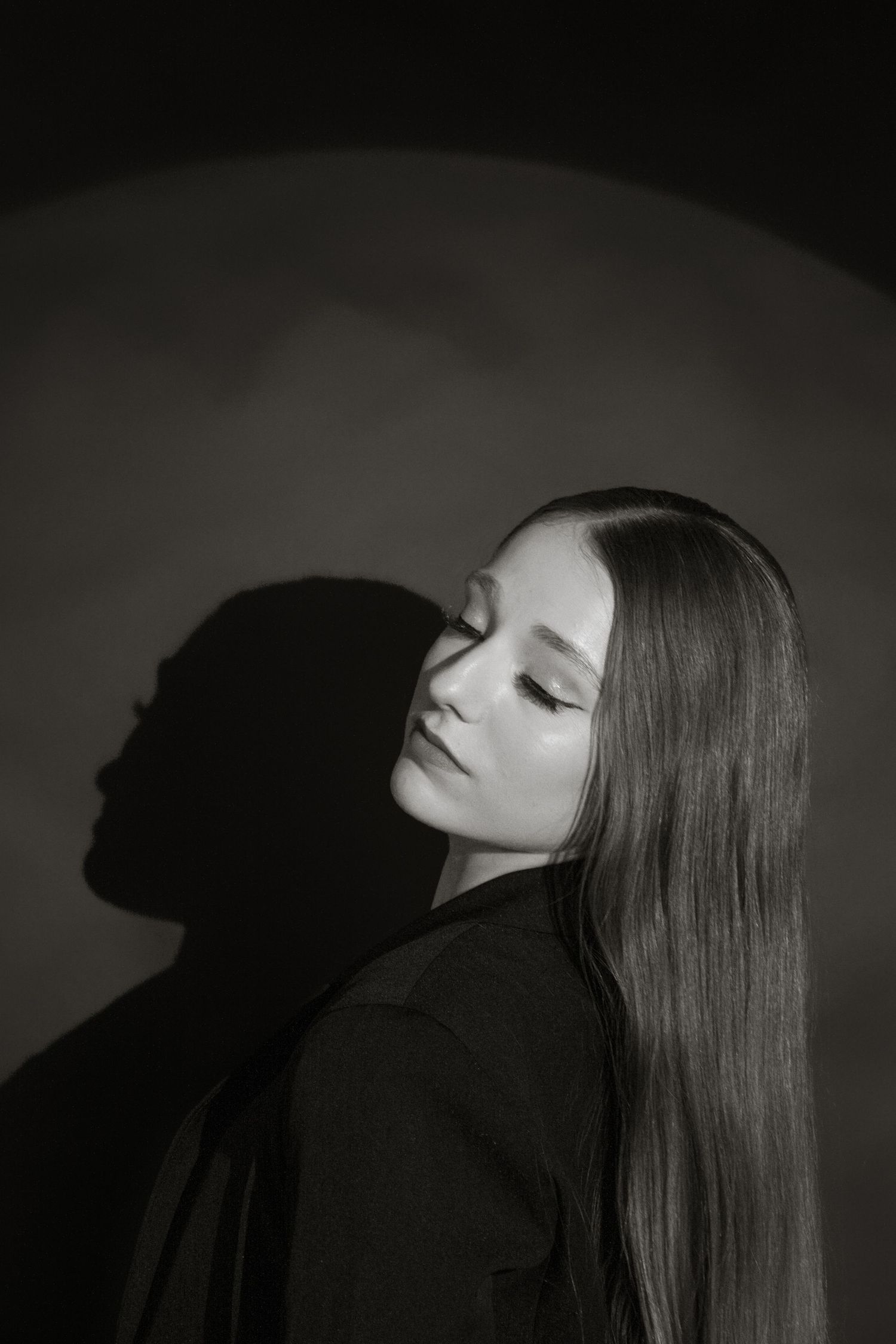 Black and white profile portrait of a young woman with long hair leaning back with eyes closed.