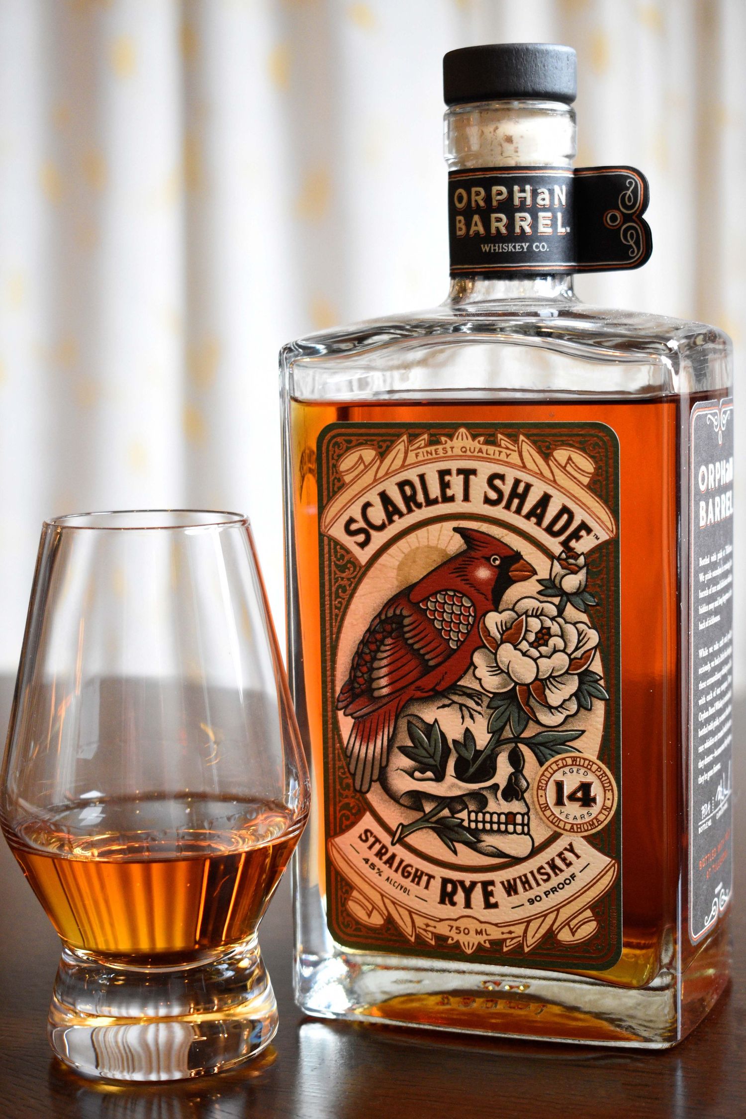 Orphan Barrel Scarlet Shade 14 Year Straight Rye Whiskey bottle with cardinal label beside a Glencairn tasting glass.
