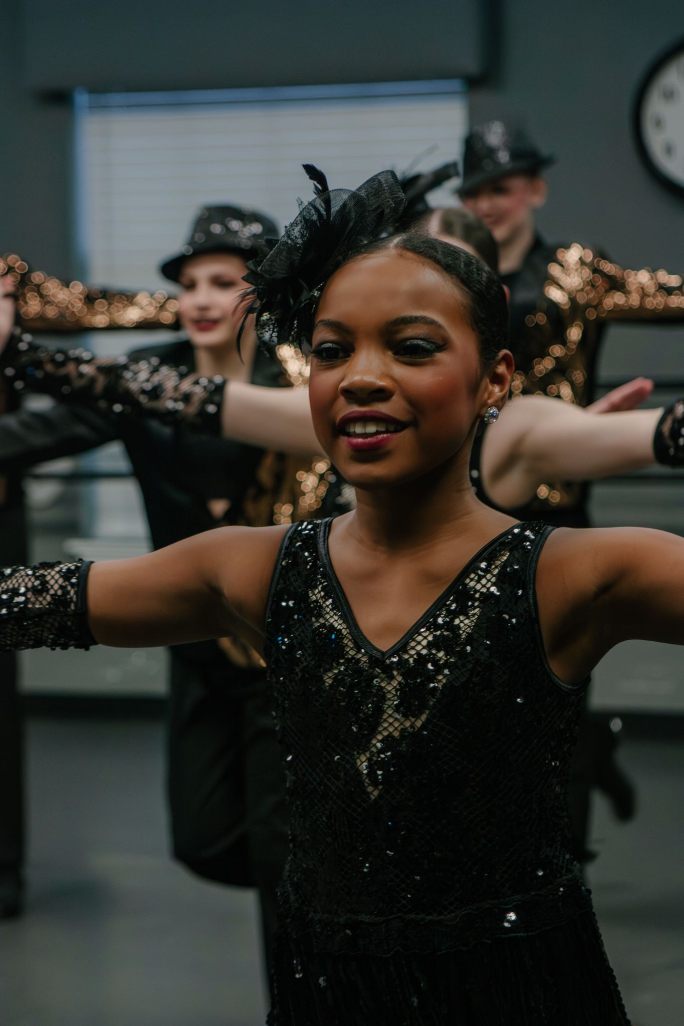 Young dancer in black sequined costume with feathered headpiece performs jazz routine.