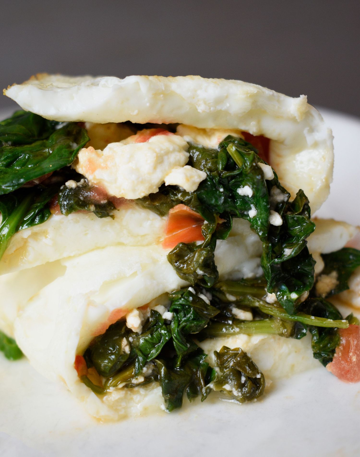 Toasted flatbread sandwich filled with sauteed kale, scrambled eggs, tomato, and crumbled feta cheese.