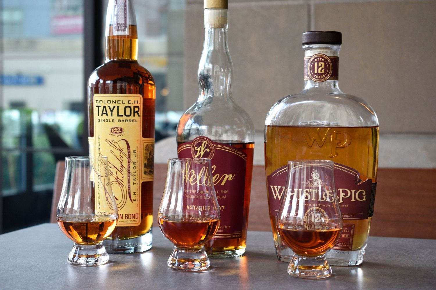 Colonel E.H. Taylor, Weller, and WhistlePig 12-year whiskey bottles with Glencairn tasting glasses.