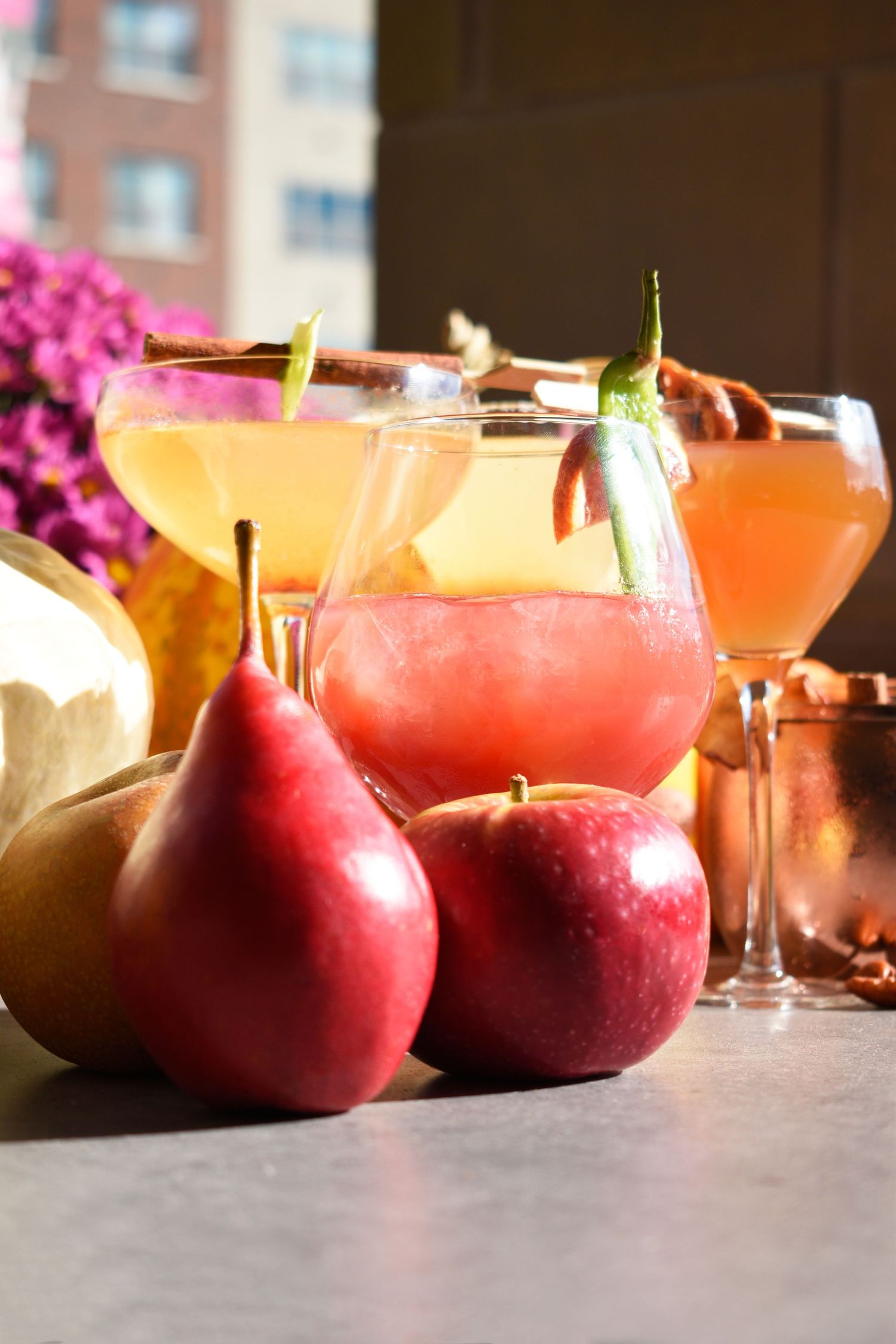 Fall cocktails with pears and apples as garnishes on an outdoor rooftop bar.