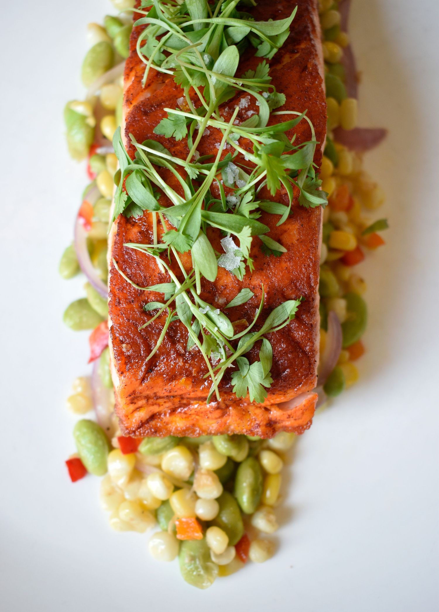 Spiced salmon fillet topped with fresh microgreens served over succotash with corn and edamame.